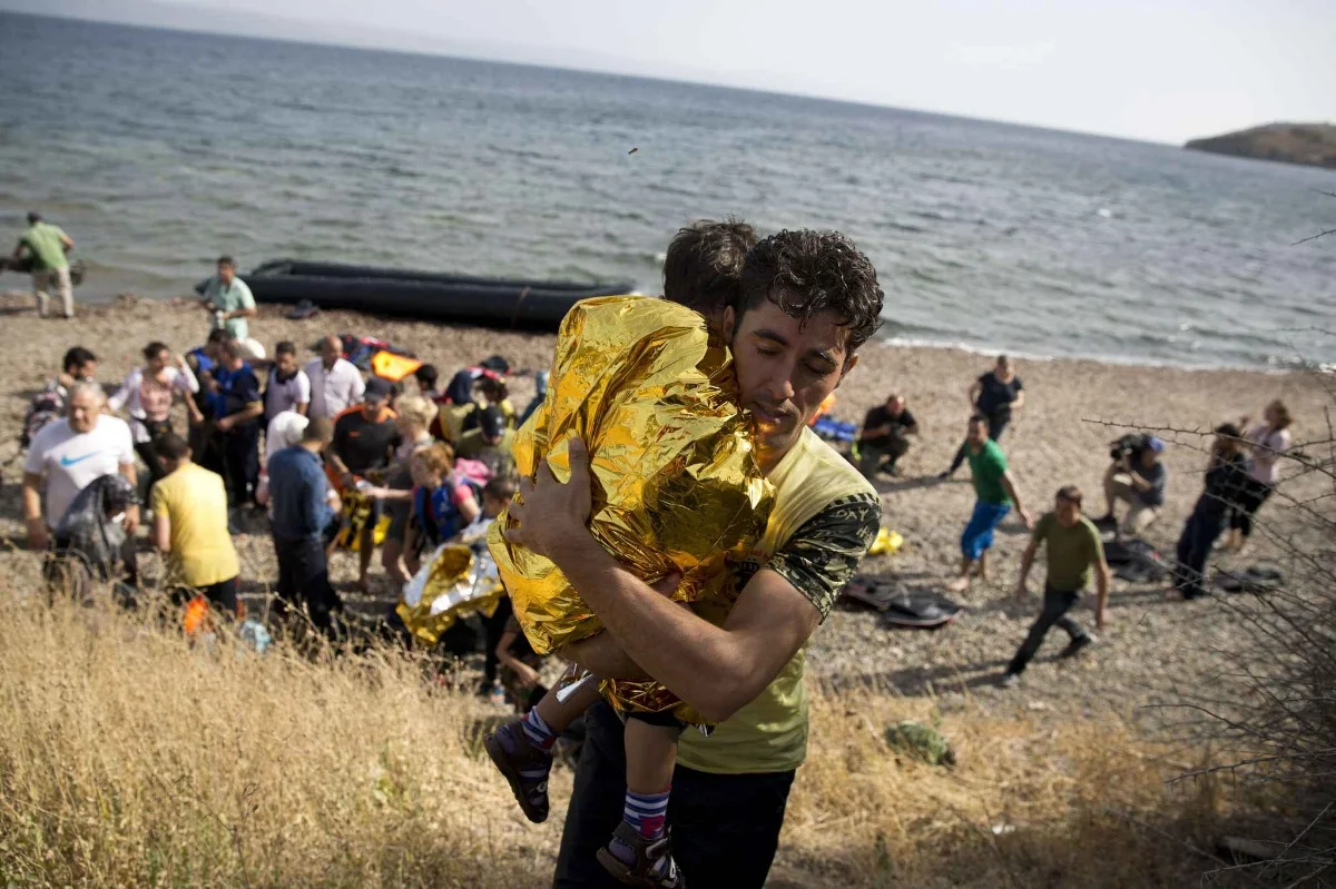 Un réfugié syrien porte un enfant après avoir traversé la Méditerranée dans un bateau gonflable depuis les côtes turques, sur l'île de Lesbos, en Grèce, le 7 septembre 2015. - Petros Giannakouris/AP/SIPA