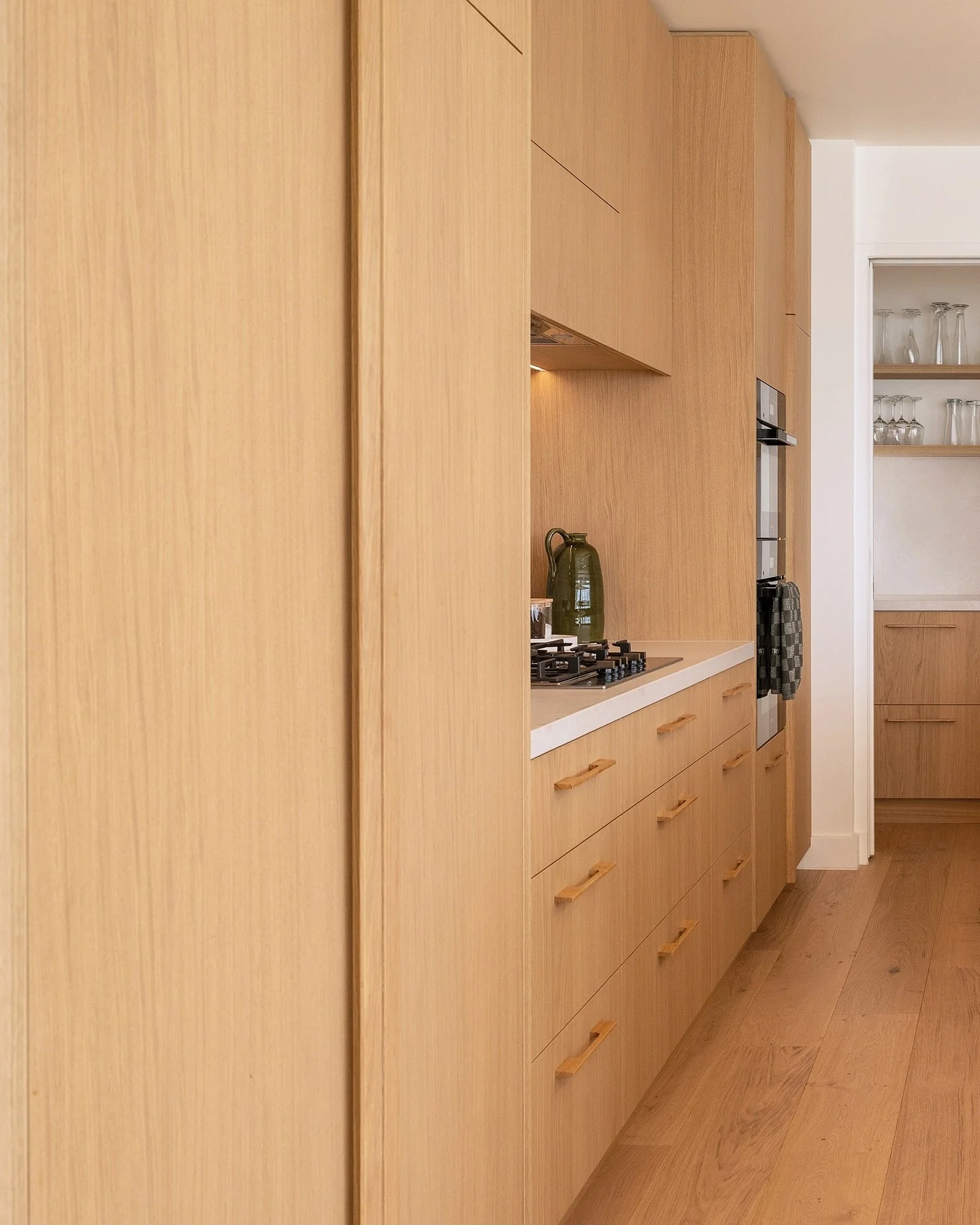 To create the quiet sophistication our clients wanted in their new home, we matched the wood tones of the floor and joinery, and even the cabinetry handles.

The soft organic, subtly patterned porcelain bench runs up the walls as a splash back to con
