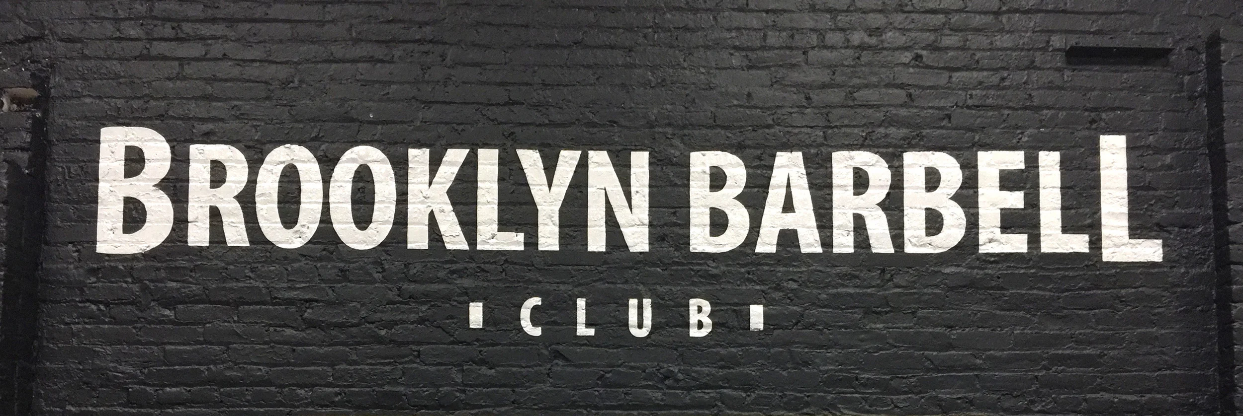 Sign on a brick interior wall in Williamsburg, Brooklyn for Brooklyn Barbell Club .