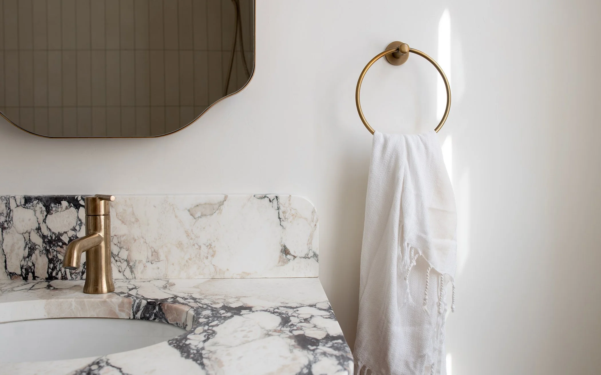 bathroom vanity with brass fixtures and calacatta viola marble