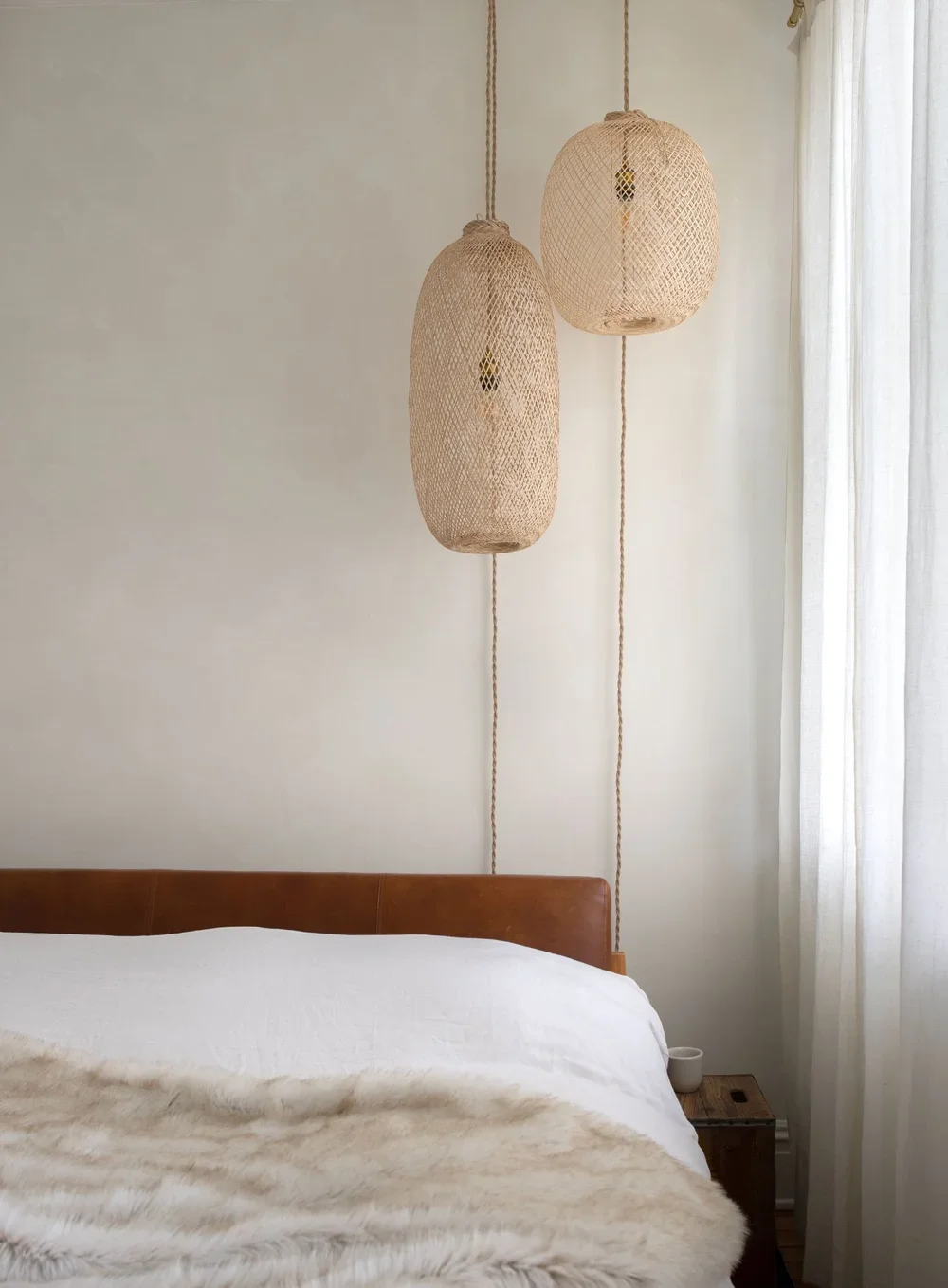 modern bedroom with rattan bamboo lanterns, linen duvet and linen curtains with textured roman clay walls