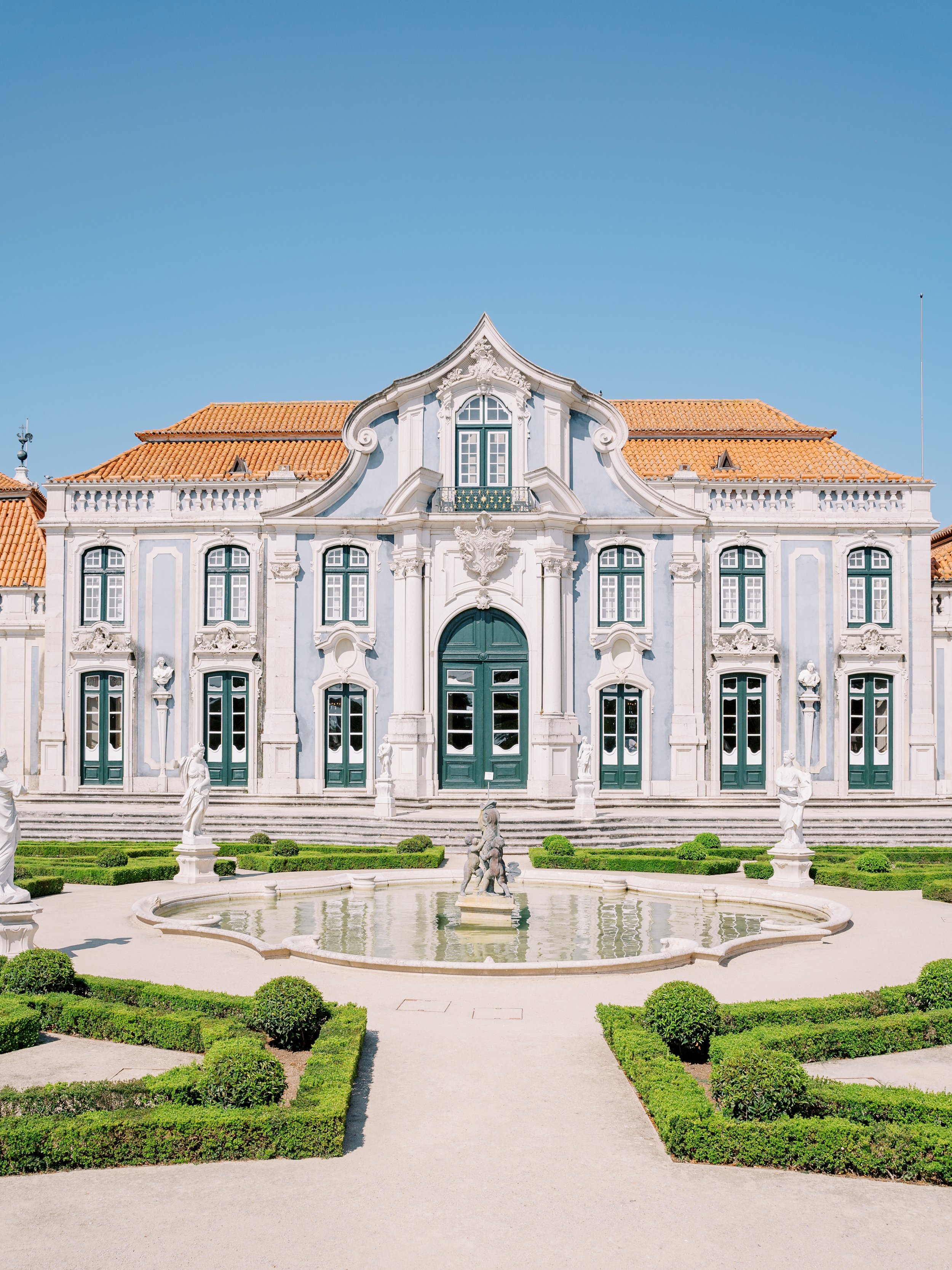 An impressive photo of the back of Palácio de Queluz with a fountain in the middle, resembling to french palaces