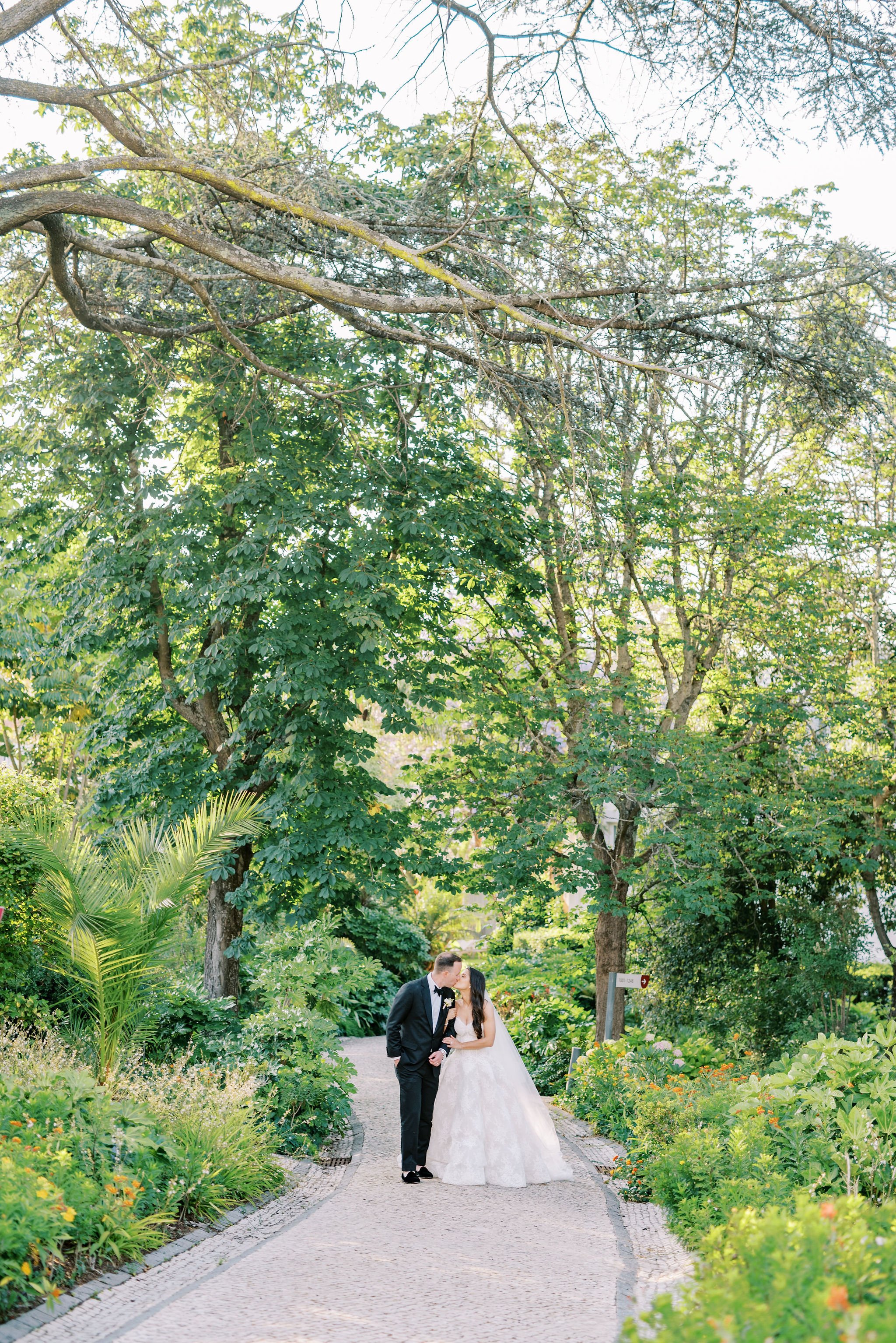 Bride and groom in the gardens of Pestana Palace Lisbon surrounded by trees