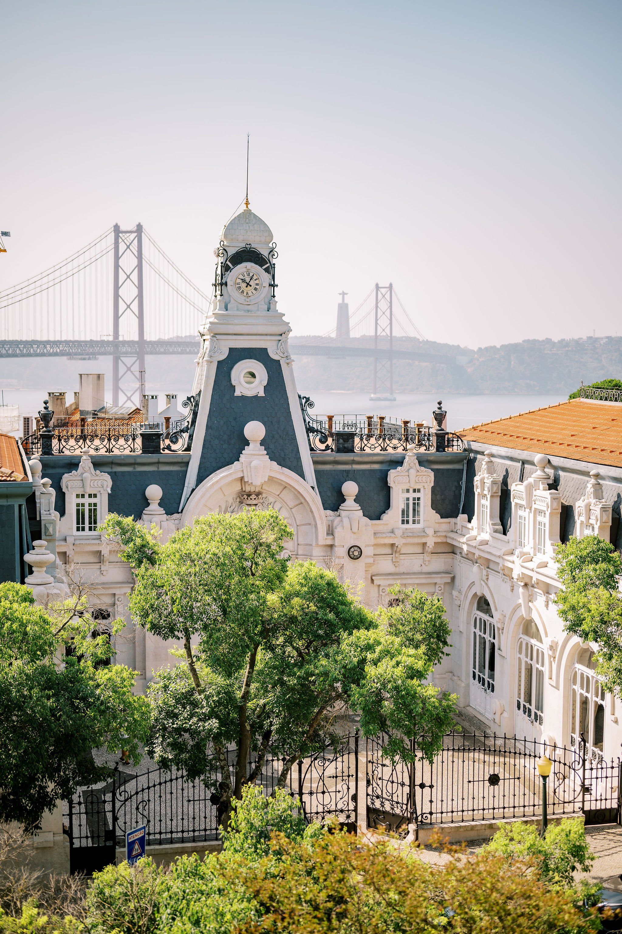 A rare view of Pestana Palace, showing the decorative tower of the building and the 25 Avril Bridge above the river Tejo and the Cristo Rei statue in the background 