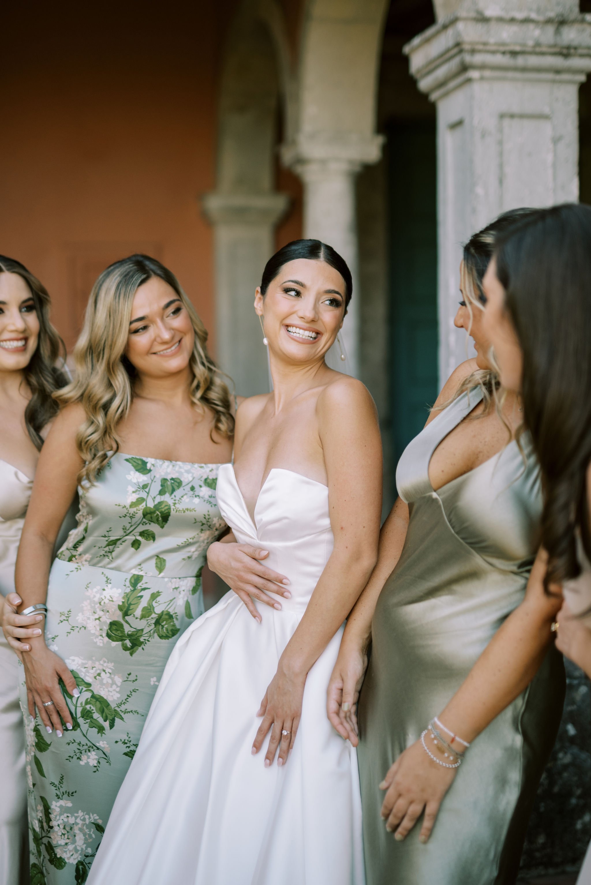 Smiling bride looking at her bridesmaids dressed in green bridesmaid dresses