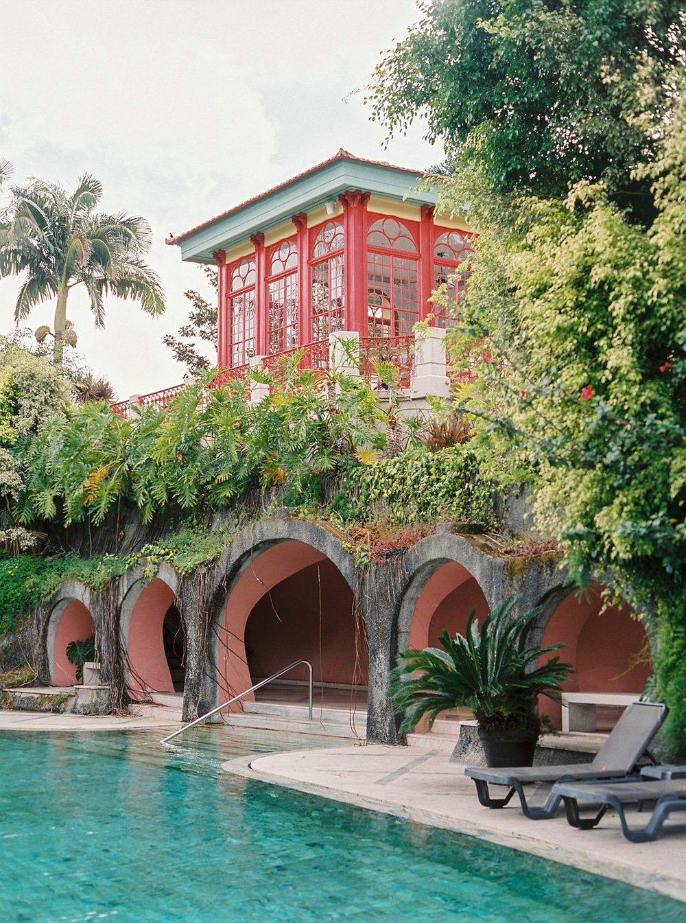 Photos of the red building in the gardens of Pestana Palace in Lisbon with the allure of the Chinese architecture, with a pool in the front