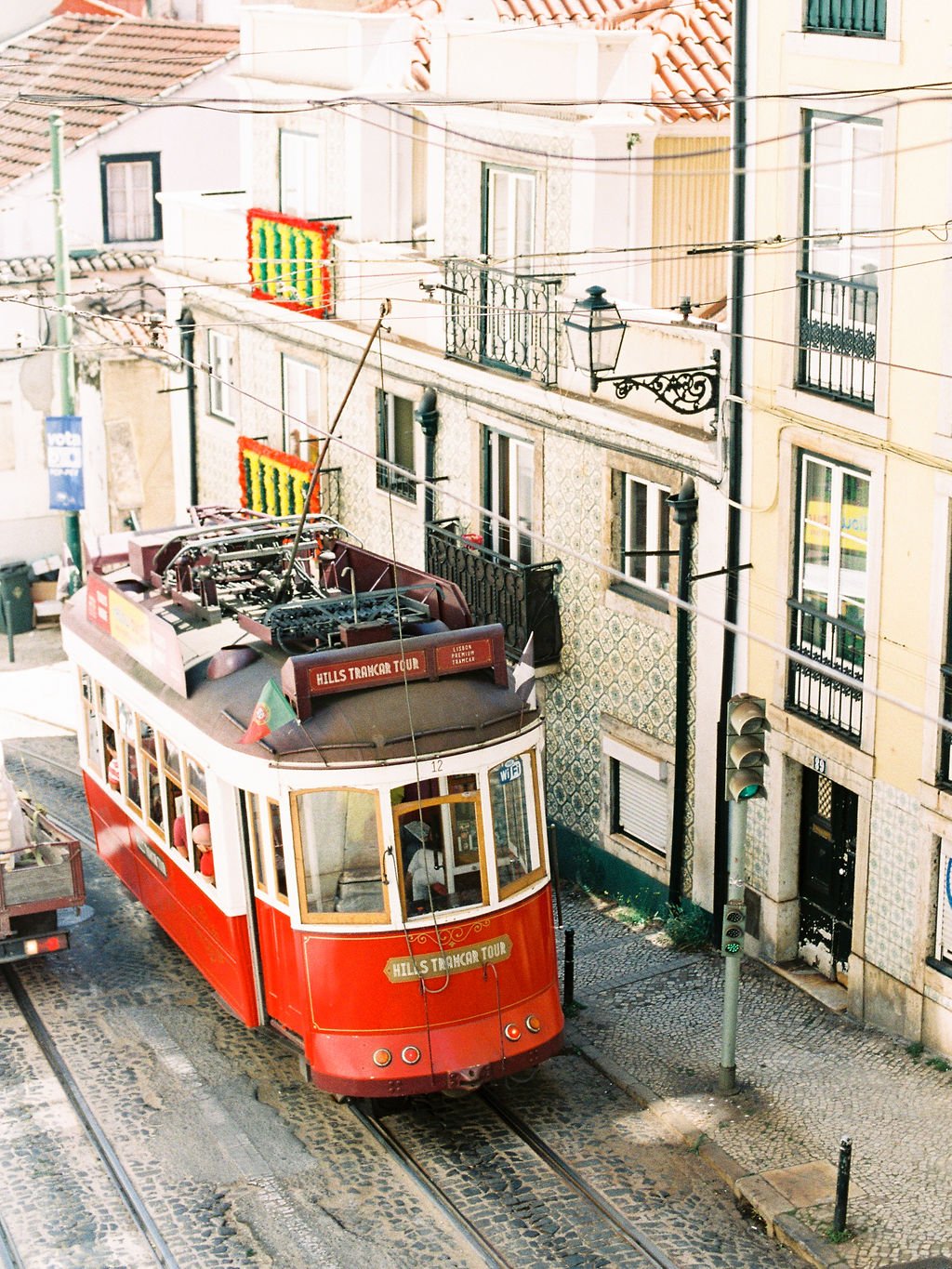 A red tram going uphill in the city Lisbon on a narrow street