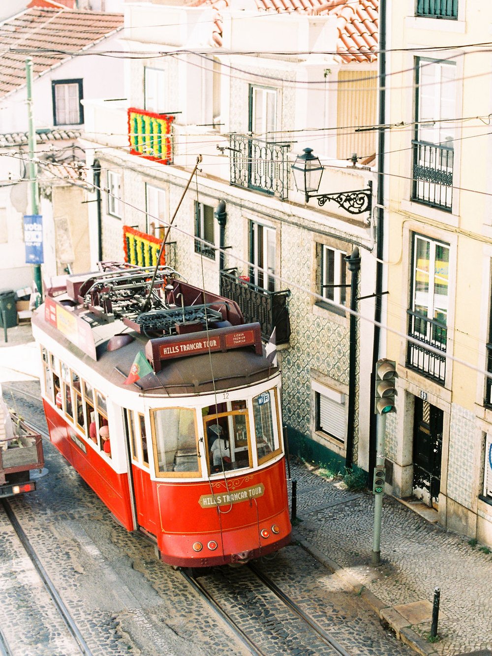 A red tram going uphill in the city Lisbon on a narrow street