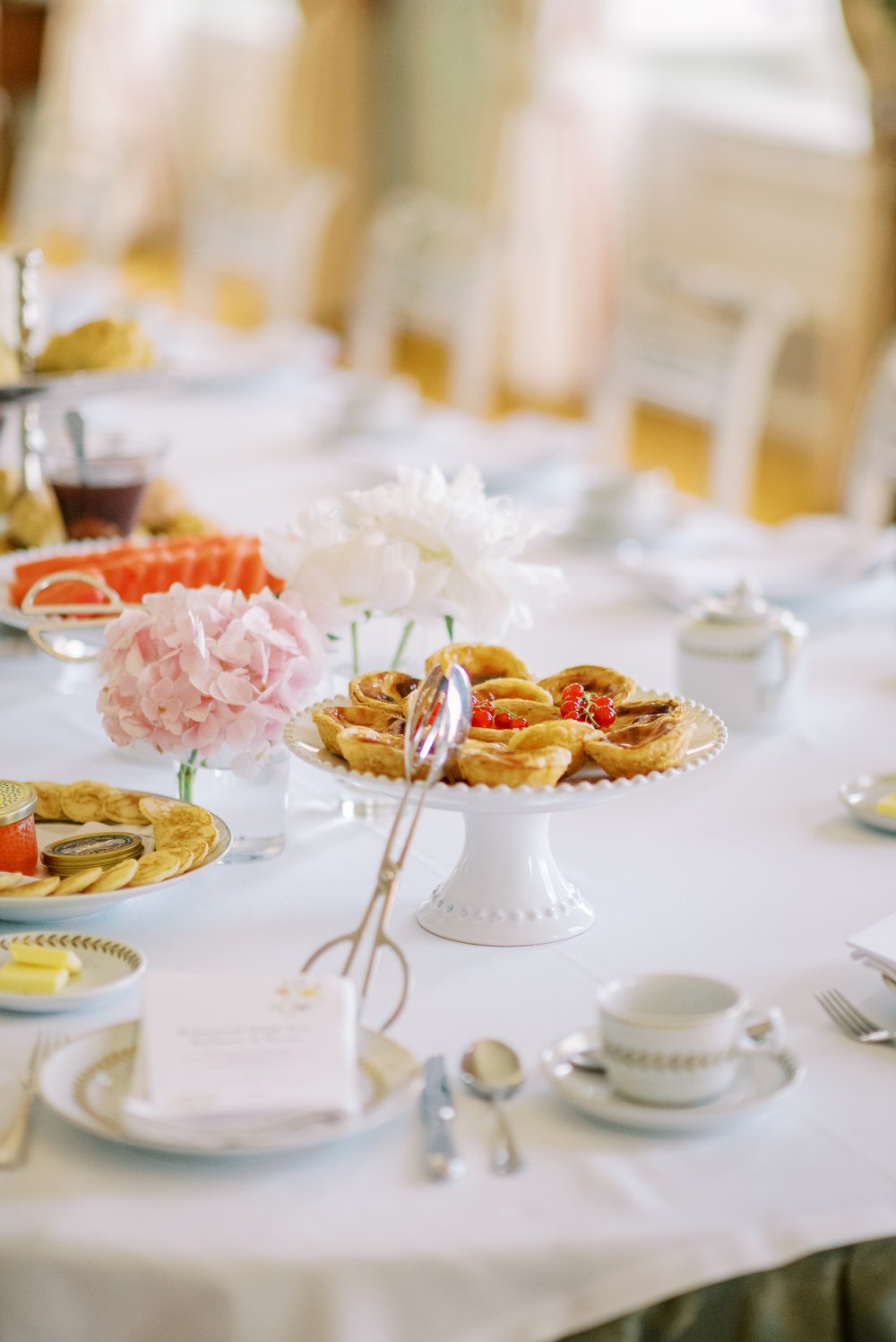 Image of a beautifully set table, and a salver full of pastel de nata