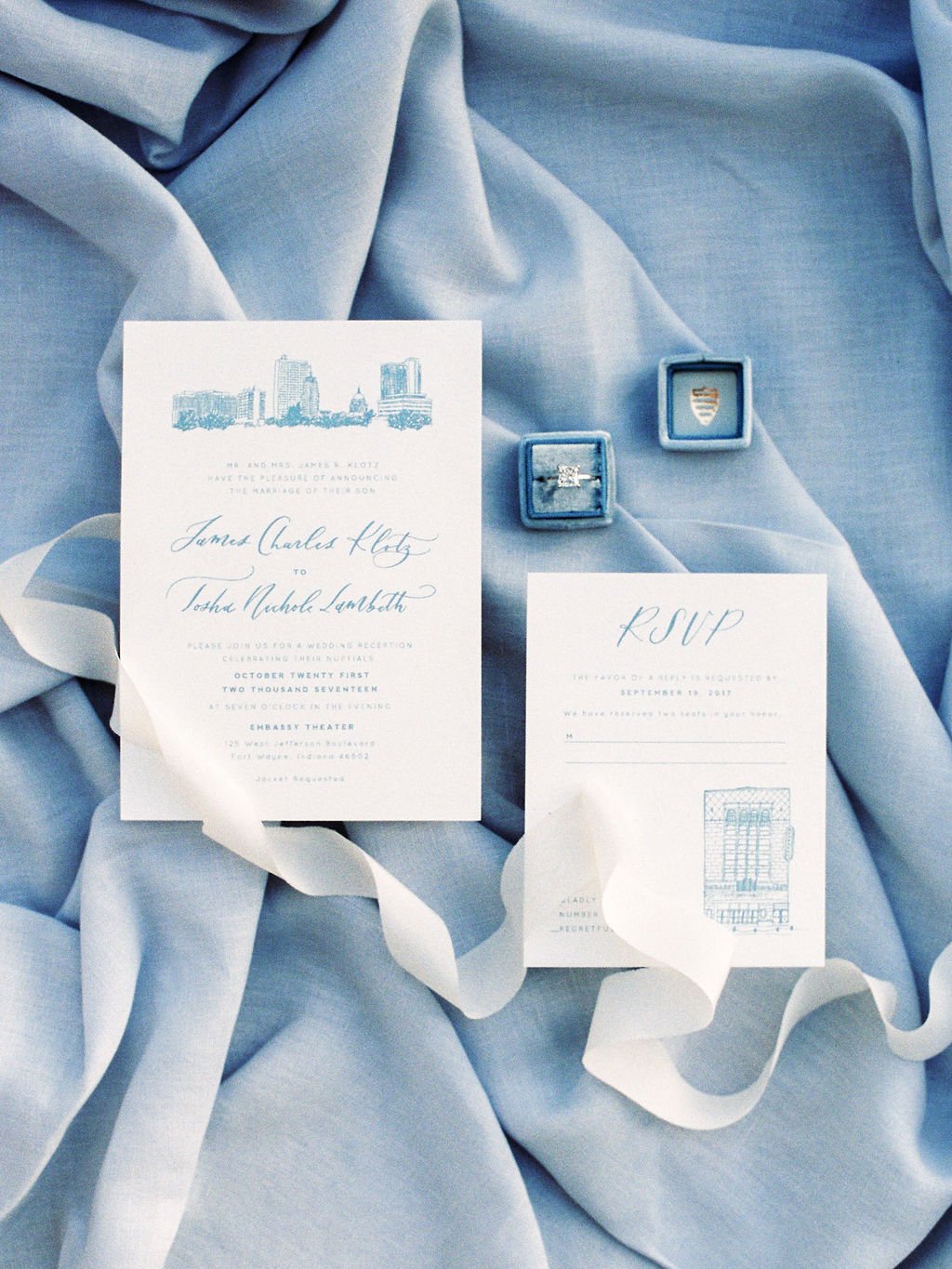 Flat lay with wedding invitation and RSVP with a blue background and white ribbon