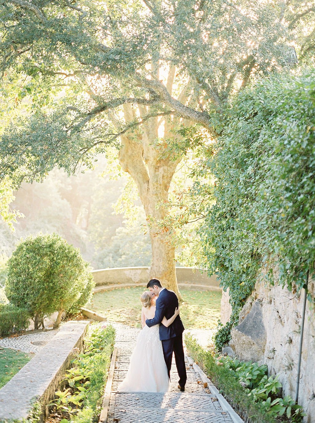 Bride and groom kissing in one of the most iconic paths behind Palácio de Seteais in the garden, on the stairs, in the golden light of a warm summer day