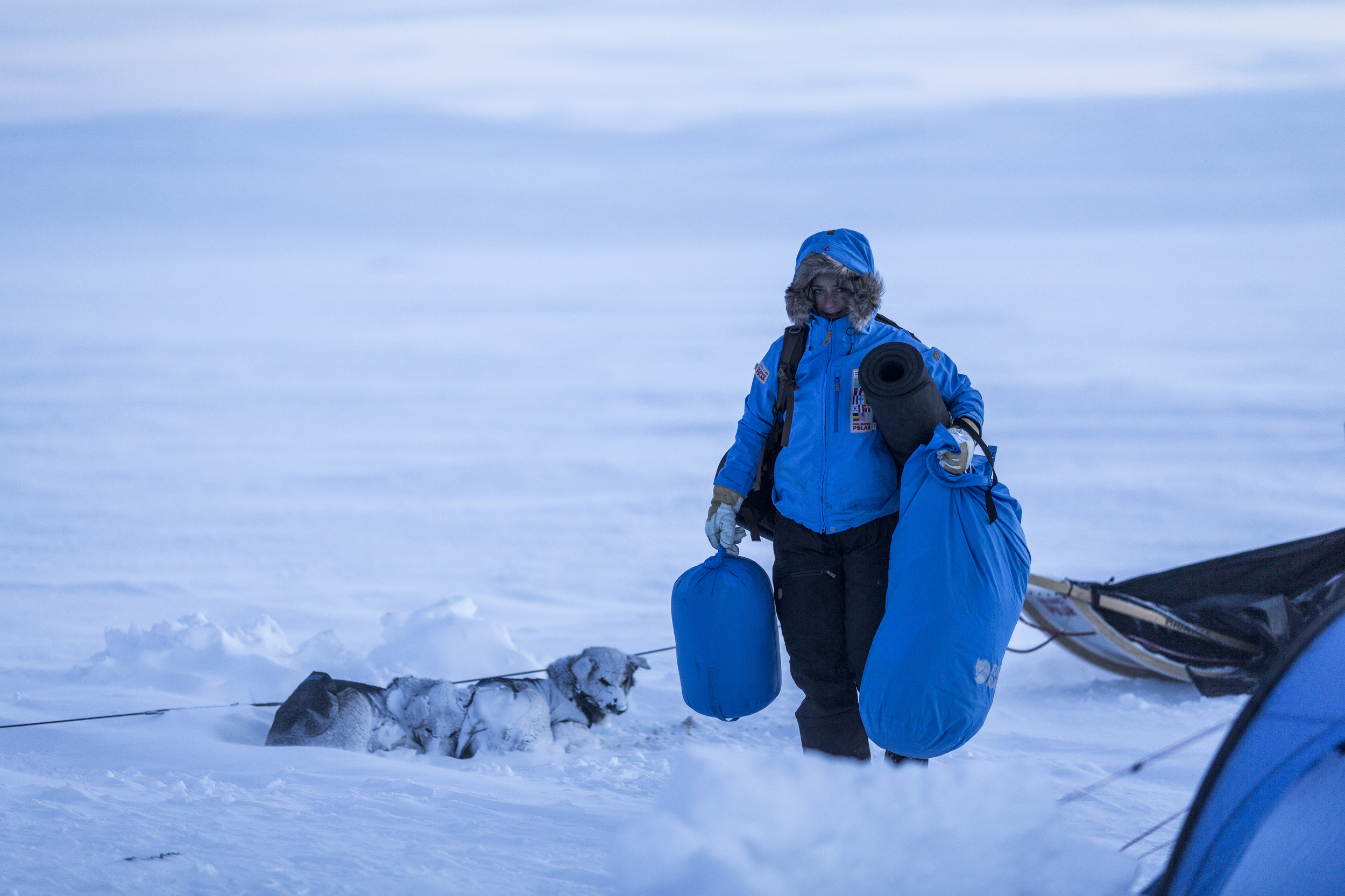 As the sun begnins to set of Råstu, German Fjällräven Polar participant Melanie Ward unpacks her sled and prepares to make camp. (Photo by Håkan Wike for Fjällräven International. All rights reserved.)