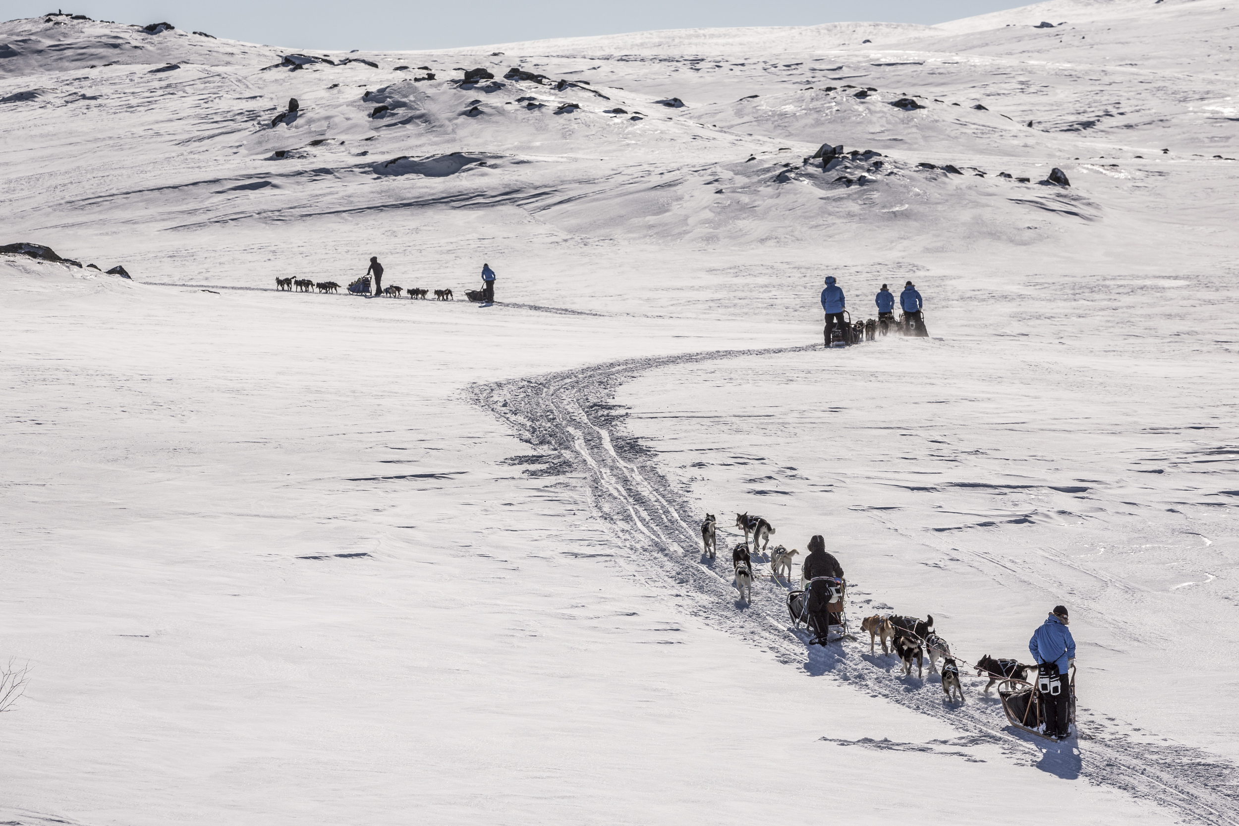 Until we descend into the tree line, the terrain around us is uniformly vast and white, with only the occasional rocky peak for visual contrast. (Photo by Håkan Wike for Fjällräven International. All rights reserved.)