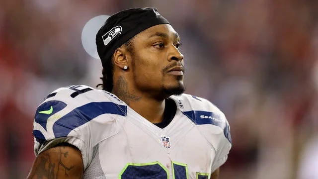 marshawn lynch facing to the right while wearing white and looking serious.jpg