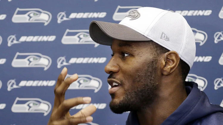 Derrick Coleman looking hot at a press release with a hat on featuring his side profile.jpg