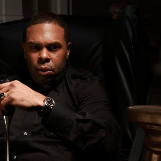 C.L. Smooth sitting in a black leather chair and looking hot and important.jpg