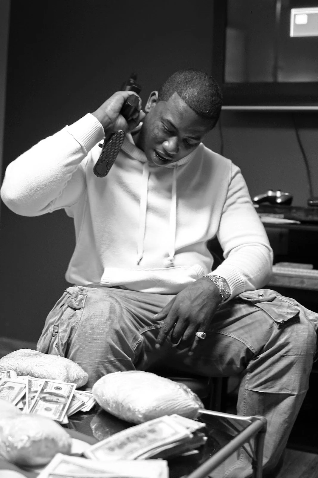 Gucci Mane holding his gun with weed coke and money on the table in front of him.jpg