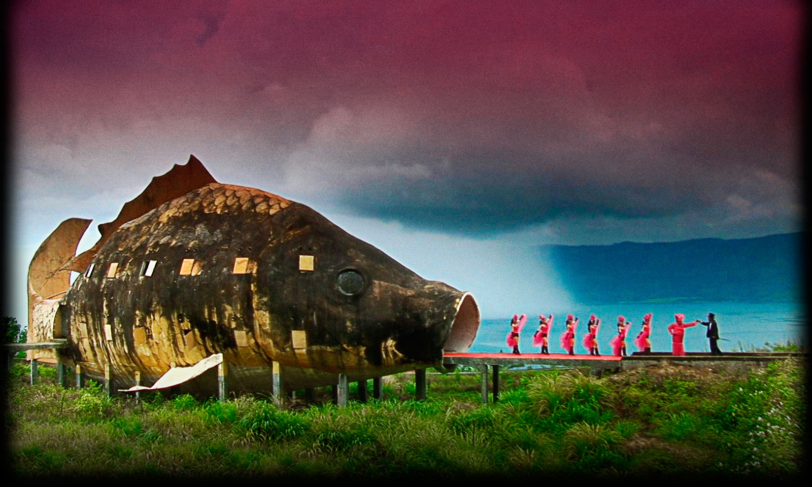 Girls in pink dresses dance into the mouth of a giant fish, a scene leading up to the final fictionalized and self-created homage to the genocidal killers. 