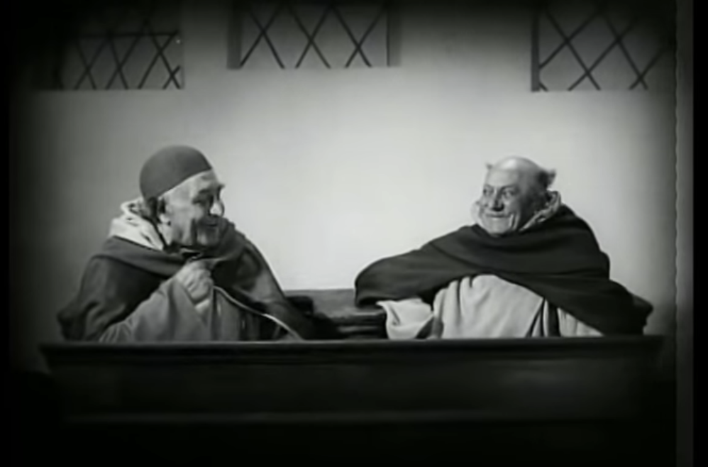 Two priests laughing at the outset of an interrogation that ends in death when Joan of Arc reveals she is unsure of how old she is. 