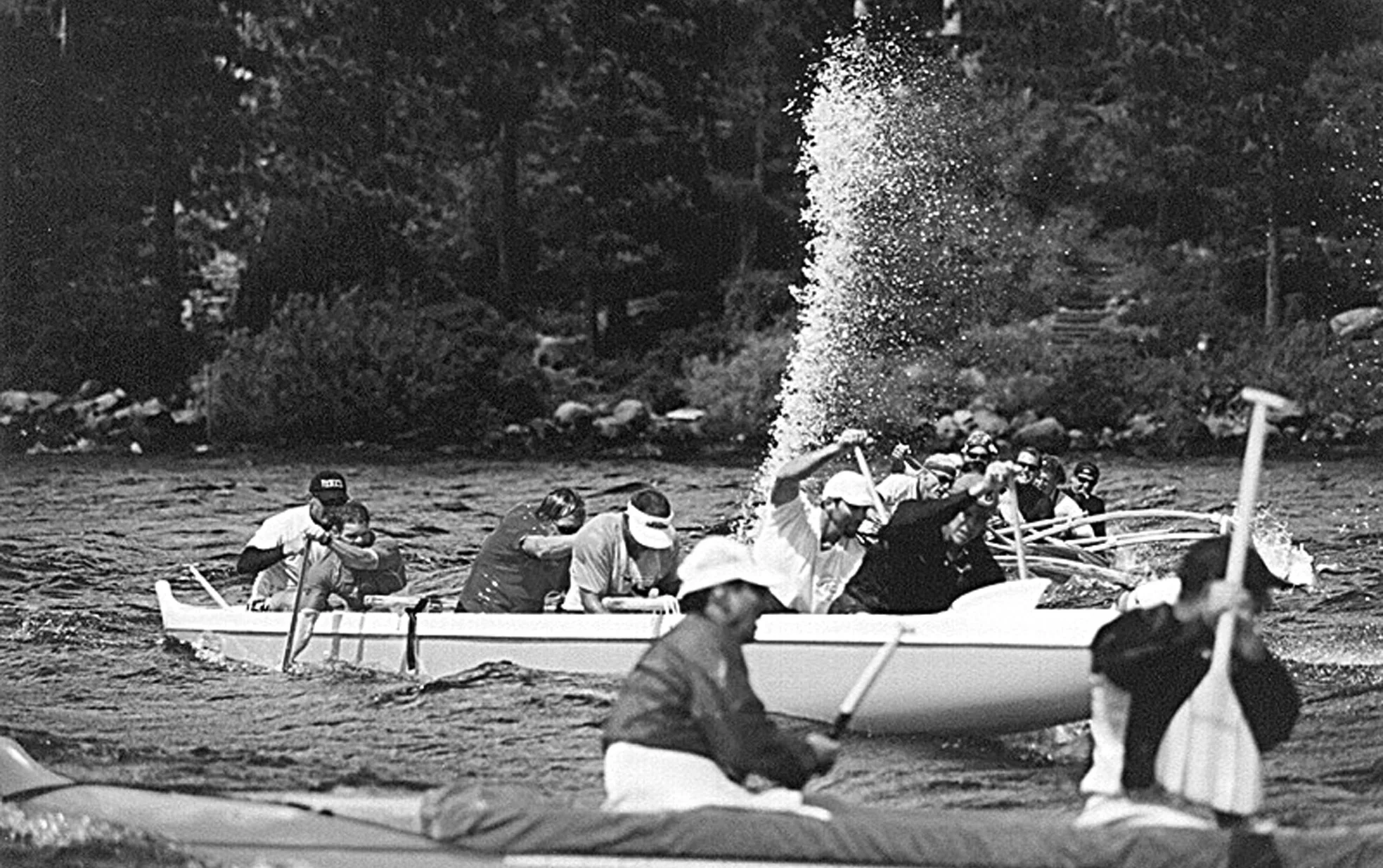 Seat 3 bailing . . . NOTE SEAT 1 HAS COME OVER / OR REMAINED ON THE LEFT AFTER THE ‘HUT’ WAS CALLED, TO PROTECT THE AMA, however, seat 1 has minimal control over canoe stability, which is more greatly offset by the middle seats (and the steerer!). If you travel to an event and paddle an unfamiliar canoe, be sure to check where the water ‘pools’ so as you know which seat will need to be bailing most. This water plume, indicates good bailing technique and by the looks of it, they are paddling downwind.
