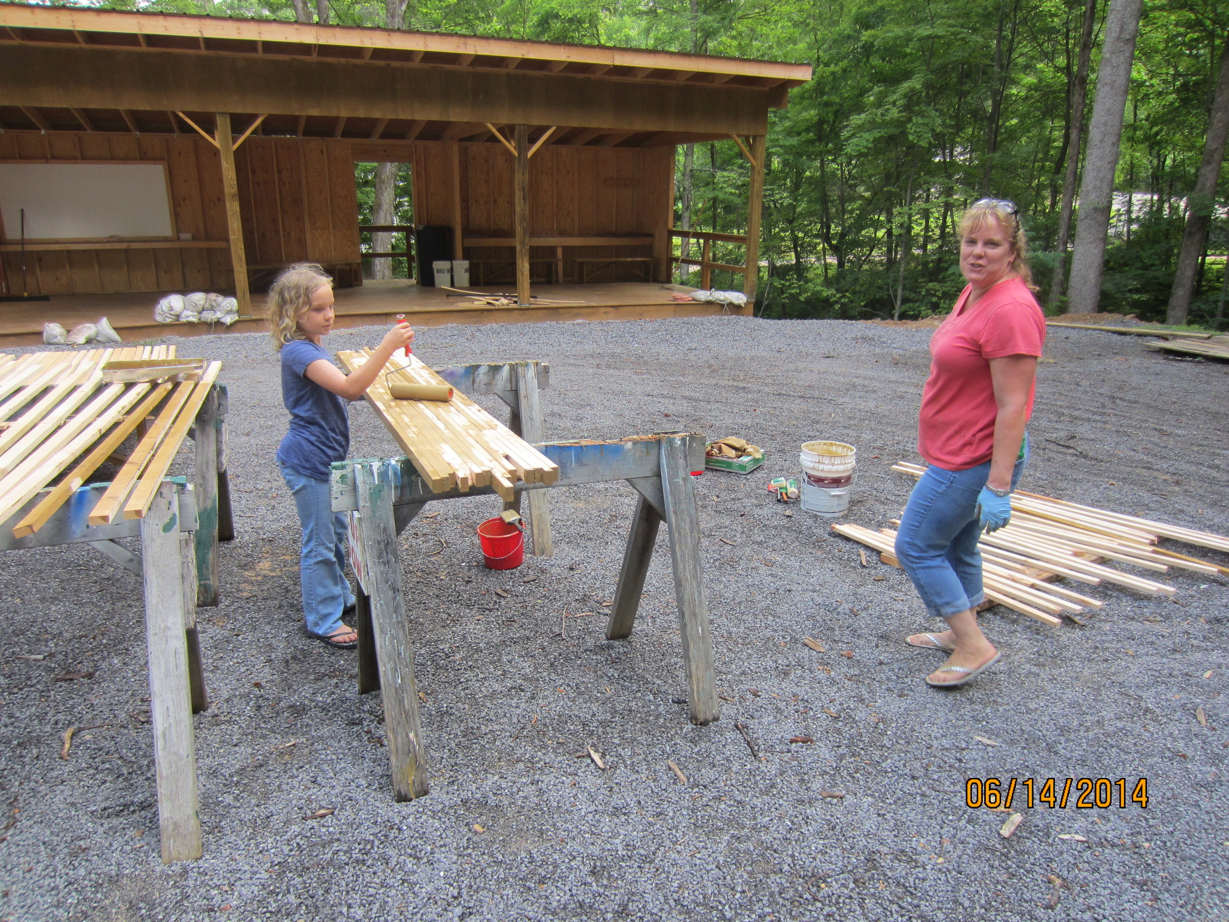 Jorja and Heide Reid finish painting the lumber needed at the new Firing Range that got wet on Friday, but is now dry enough to paint.