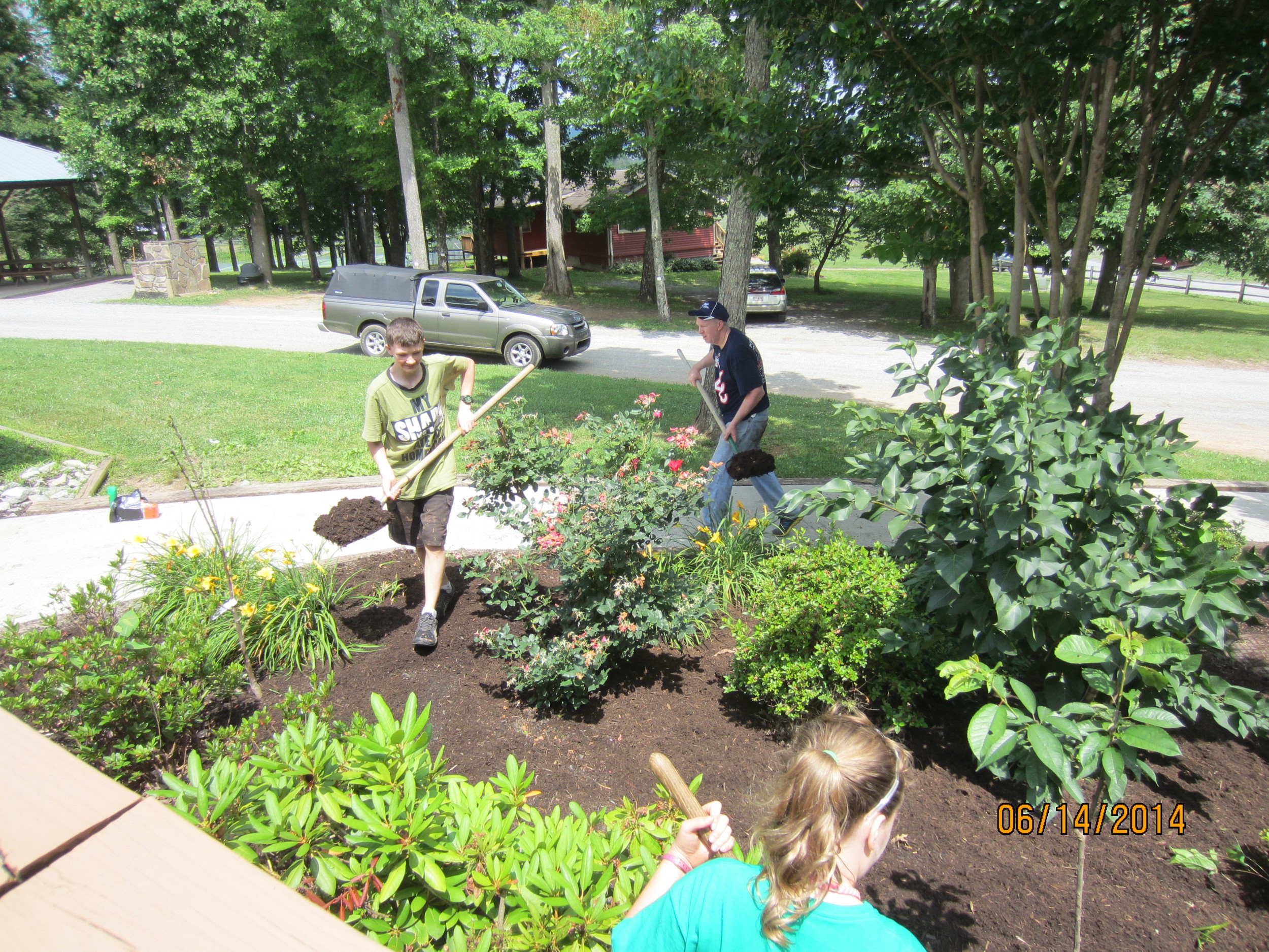 Oleg, Allie and Jonathan Reid mulching the beds around the Dining Hall.