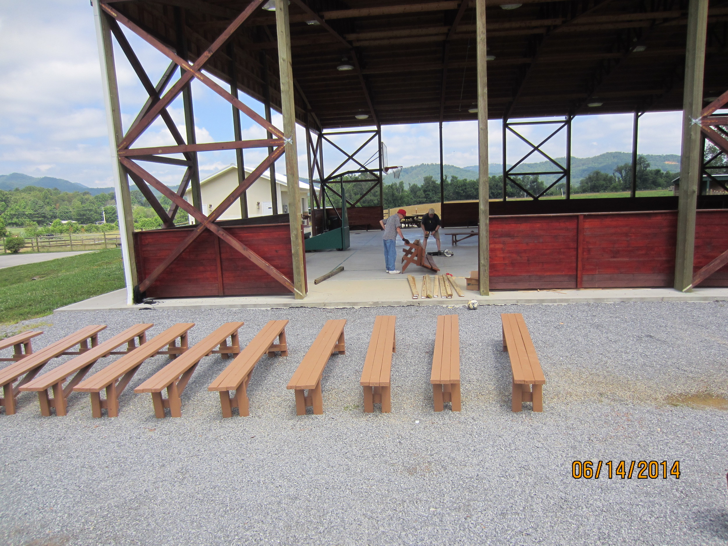 The benches constructed Friday have now been painted and are ready for deployment. In the background Fred Allen and Evan Stout discuss repair of an old bench.