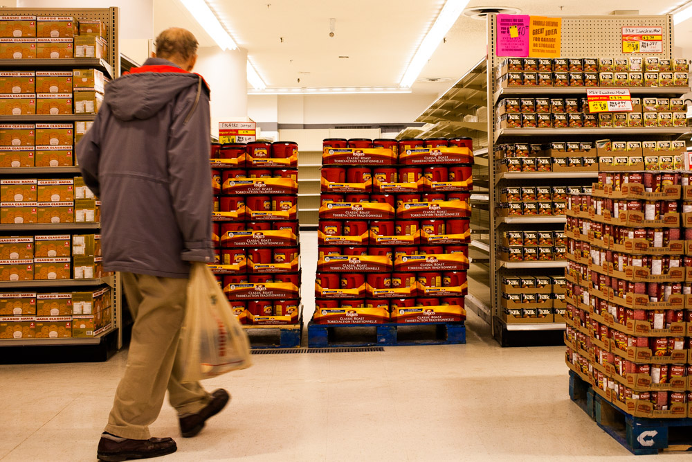 A customer wanders past pallets of cookies, coffee, canned meat, and soup.