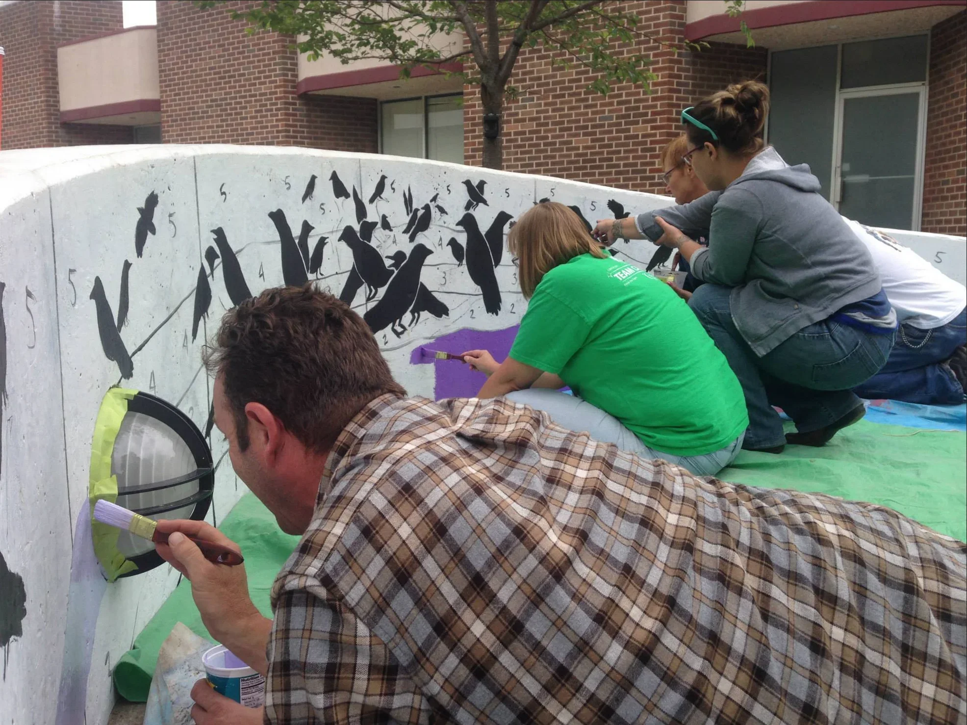  Volunteers help artist Jessie Reich paint the Exchange St. Crow mural.  Photo by  Art for Auburn  
