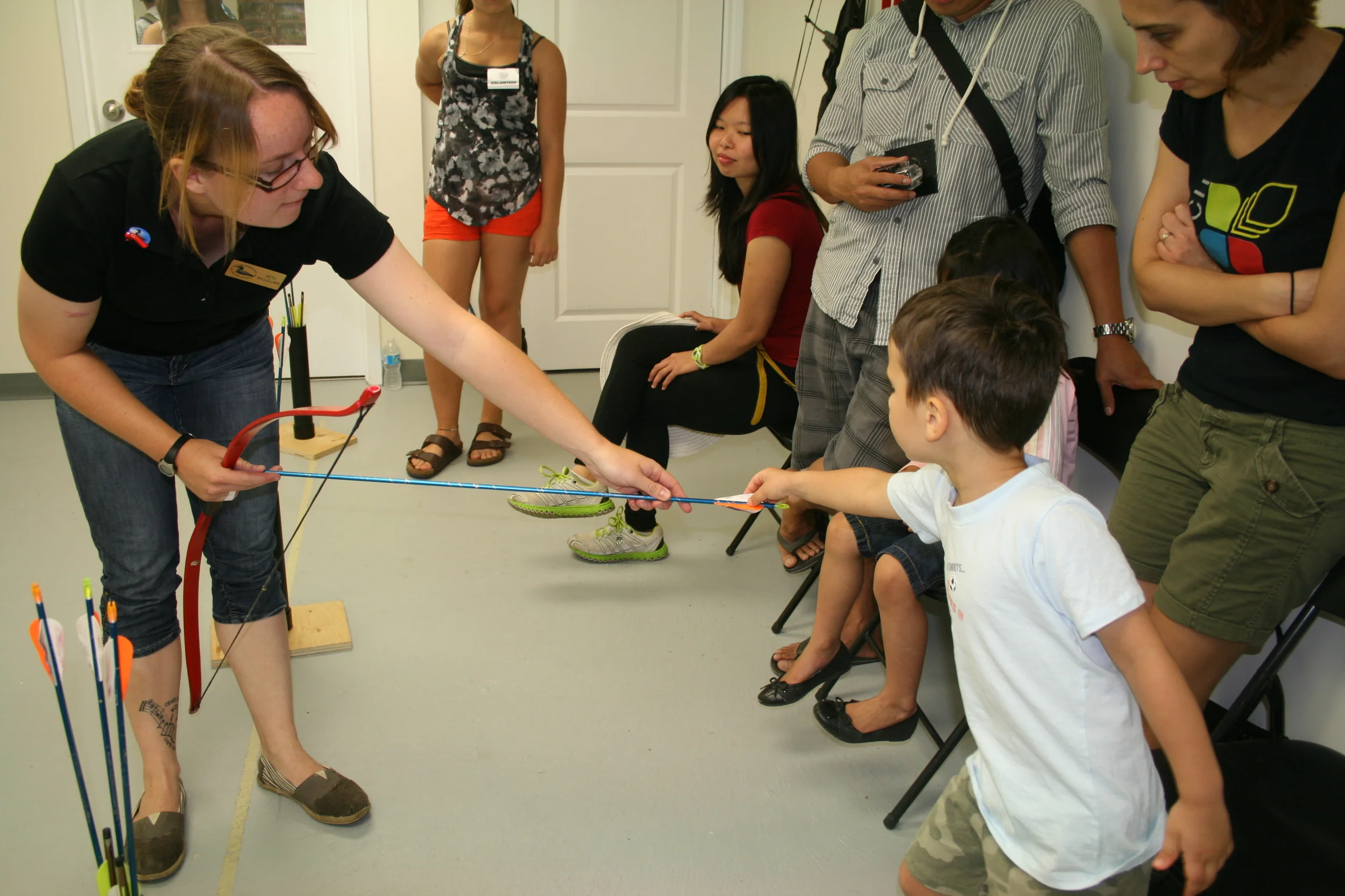 OFAH staff talk to New Canadians Centre visitors about the different 
parts of an arrow during instruction on the Excalibur Archery Range.