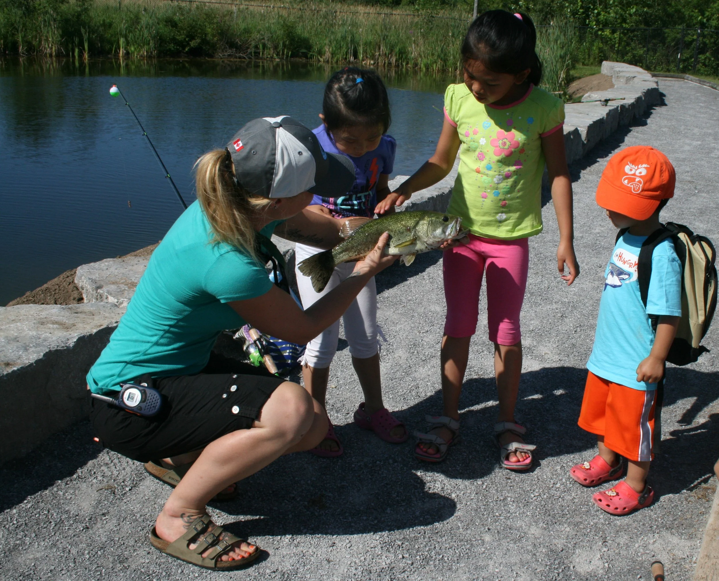 An OFAH staff member teaches a group of children about their catch before releasing it back into the pond.