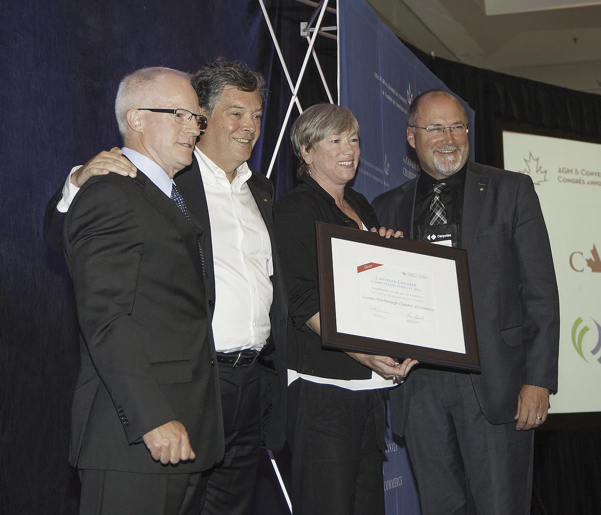 At far right: Peterborough Chamber's Manager of Membership Services Karen August and President & CEO Stuart Harrison pictured on stage accepting award