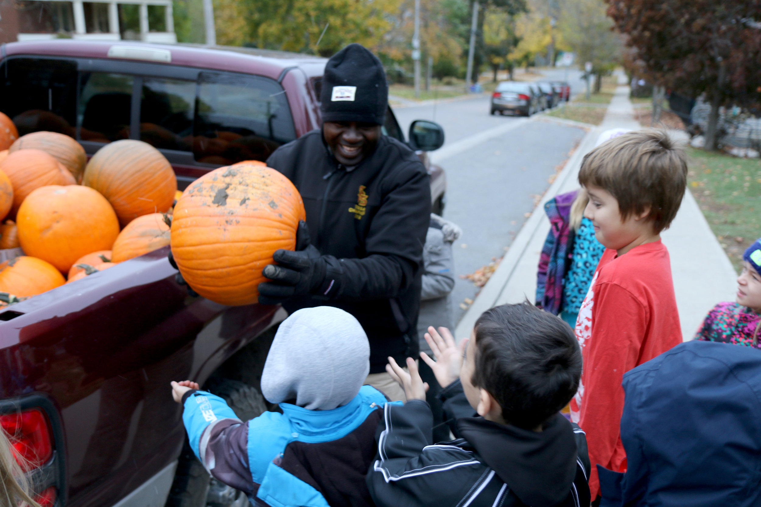 Louis distributes pumpkins to happy students at Immaculate Conception