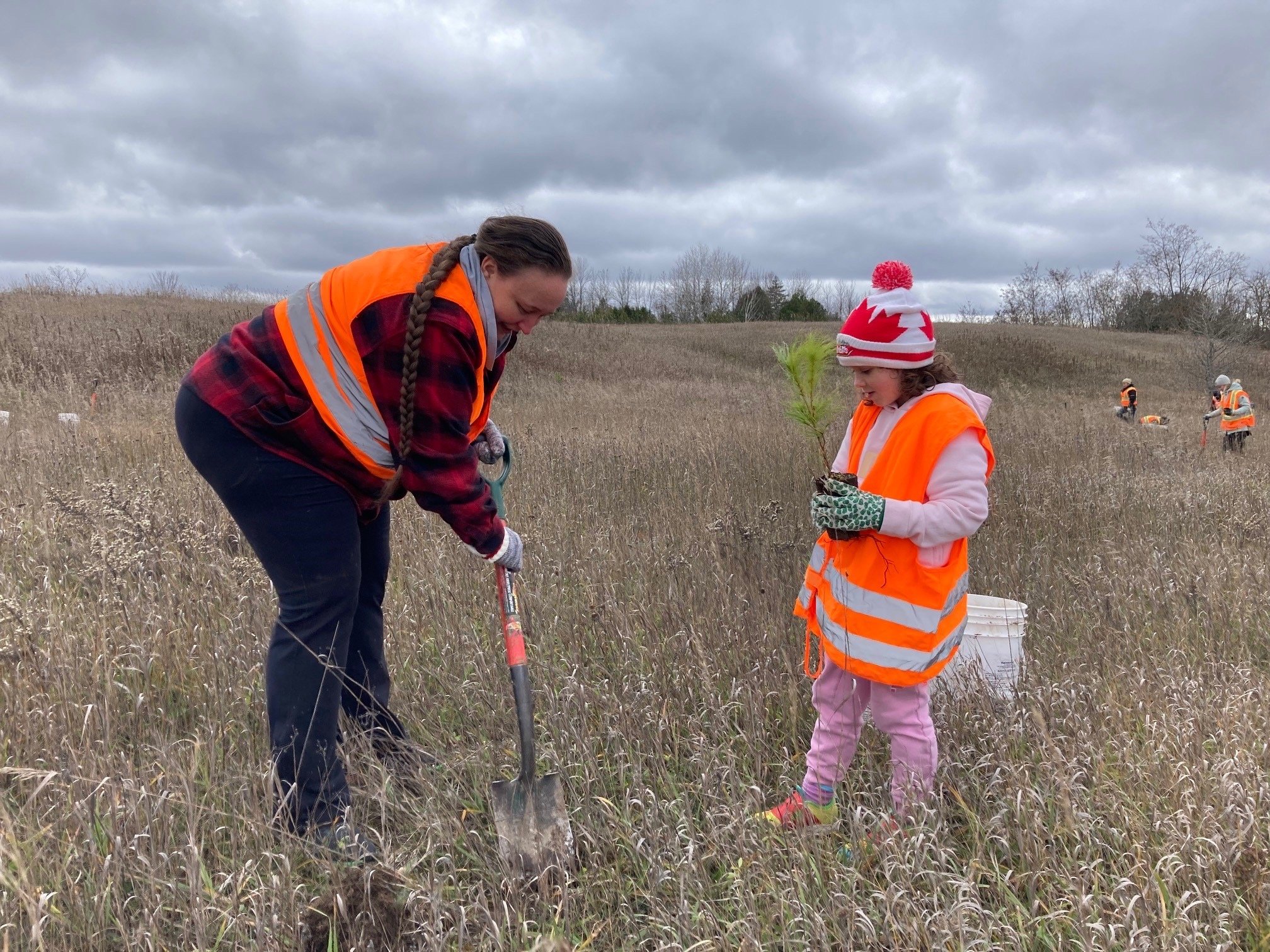 Janique Labelle (left) helps Aryanne Labelle dig a hole to plant a tree at the former gravel pit site. 
