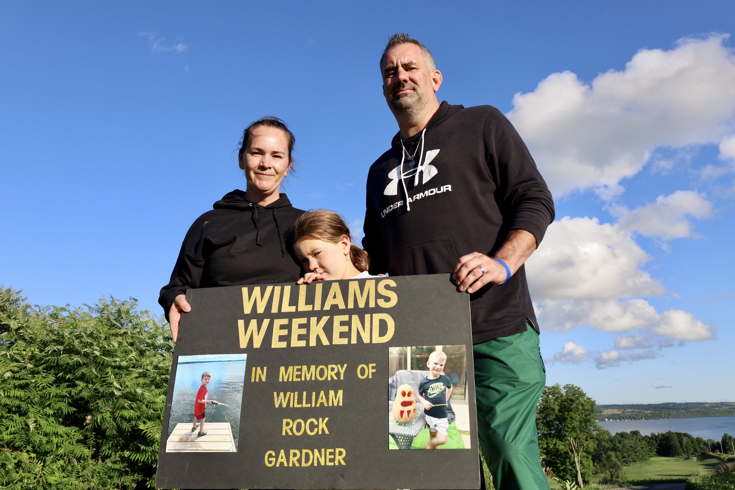 Elizabeth, Aurora and Matthew Gardner on the putting green of Bellmere Winds Golf Resort with the memorial poster of William in his memorial tournament. All photos by David Tuan Bui.