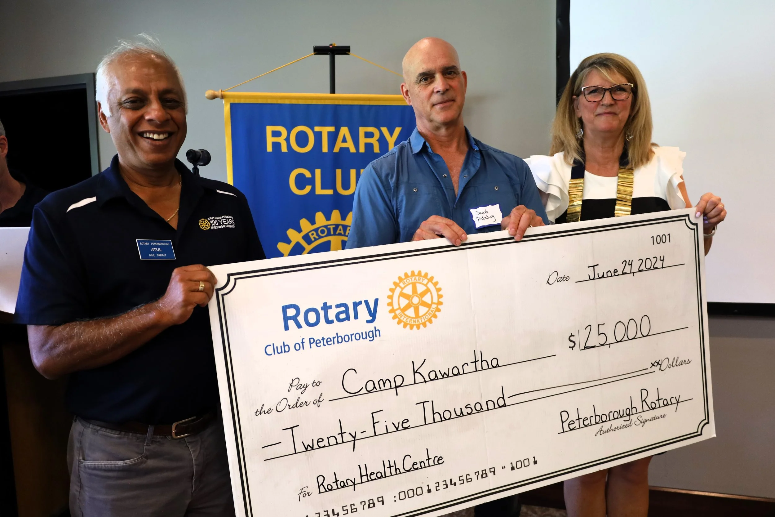 Atul Swarup, Rotary Volunteer (left) and Halman-Plumley (right) present the last $25,000 of their $100,000 donation to Jacob Rodenburg of Camp Kawartha for its Health Centre. 