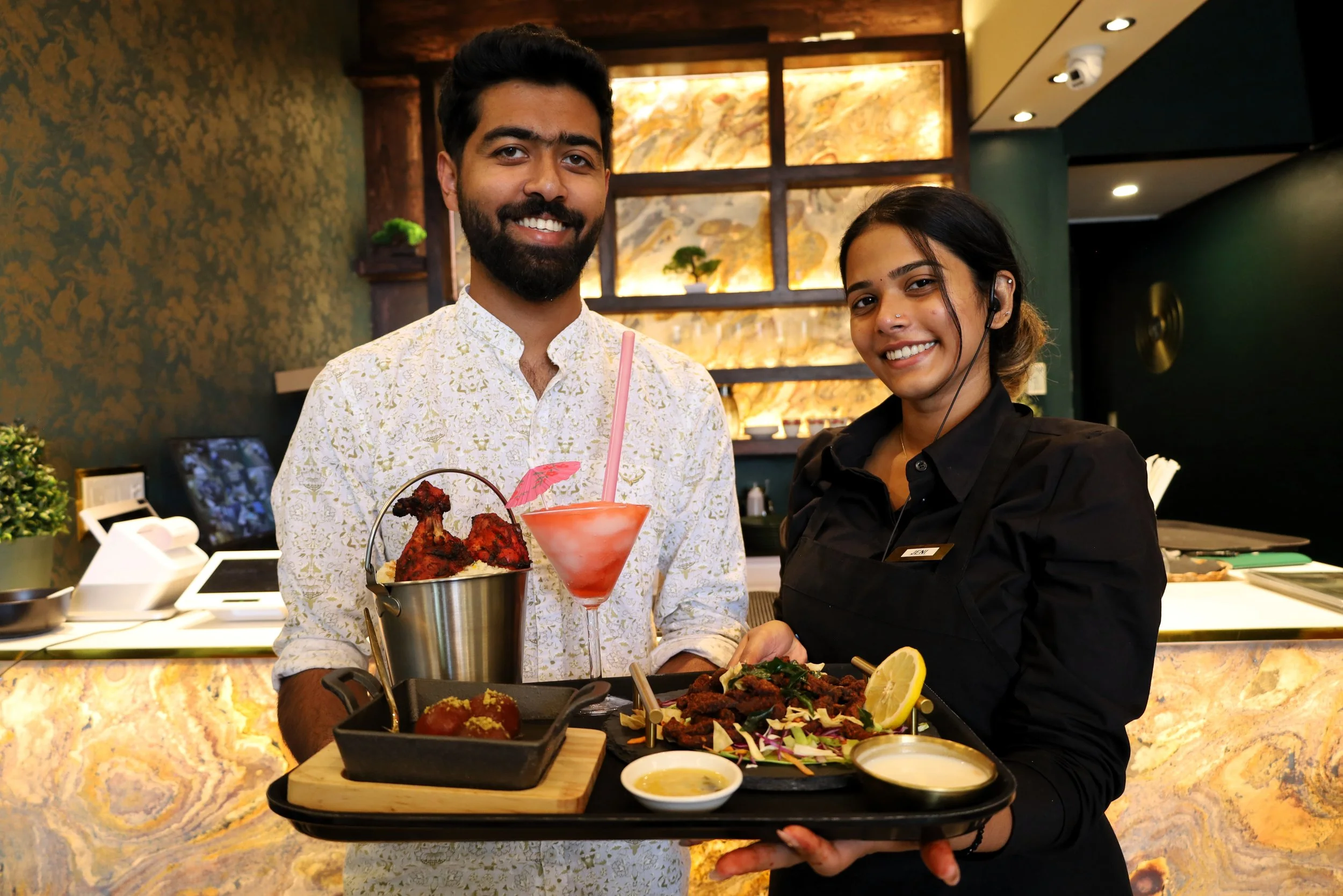 Joyal Antony, Malabar co-owner (left) with server Jeni (right) showcasing chicken biryani, beef dry fry, galub jamun and strawberry daiquiri mocktail. All photos by David Tuan Bui.