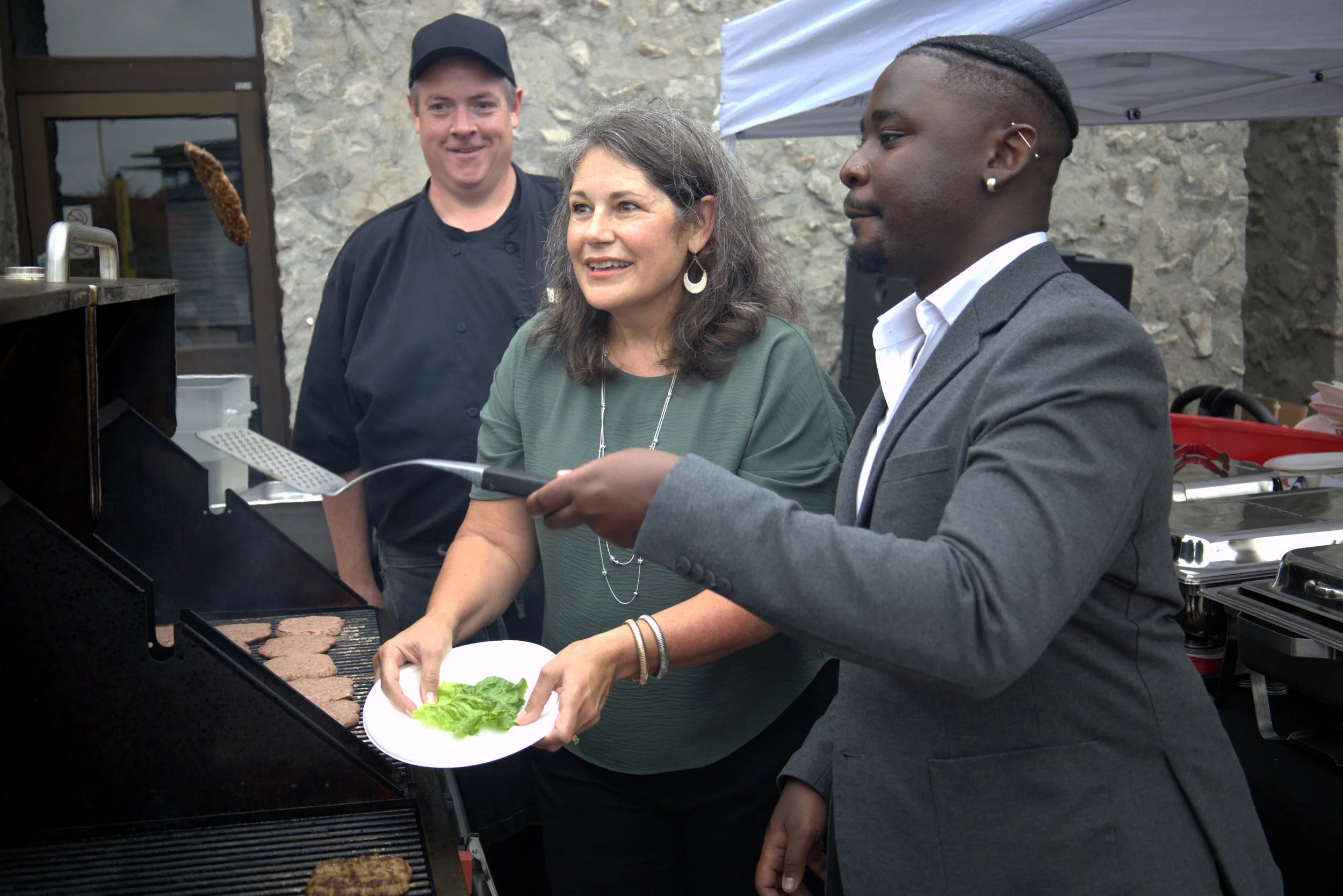 Julie Davis, Trent VP of external relations, marketing and communications about to catch a fresh burger patty off the grill from Jason Seguya, United Way CEO. All photos by David Tuan Bui.