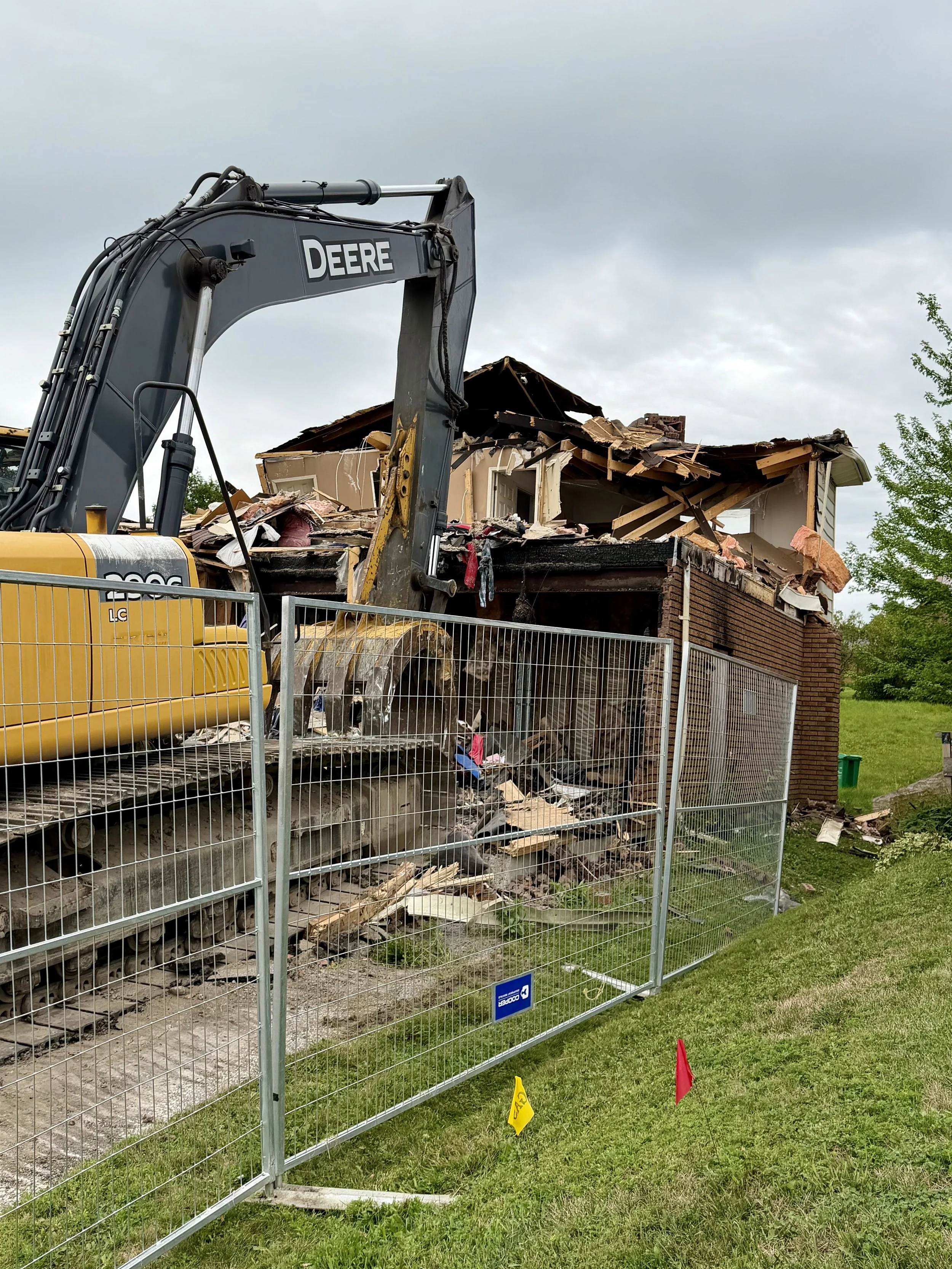 An excavator begins dismantling the structure that has stood on Woodglade Boulevard since the 2022 fire. (Photo by Scott Arnold)