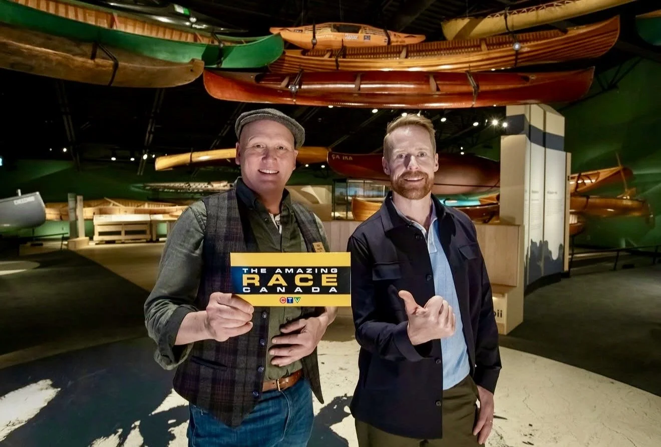canadian canoe museum curator jeremy ward showing a clue card alongside the amazing race canada host jon montgomery  in side the museum