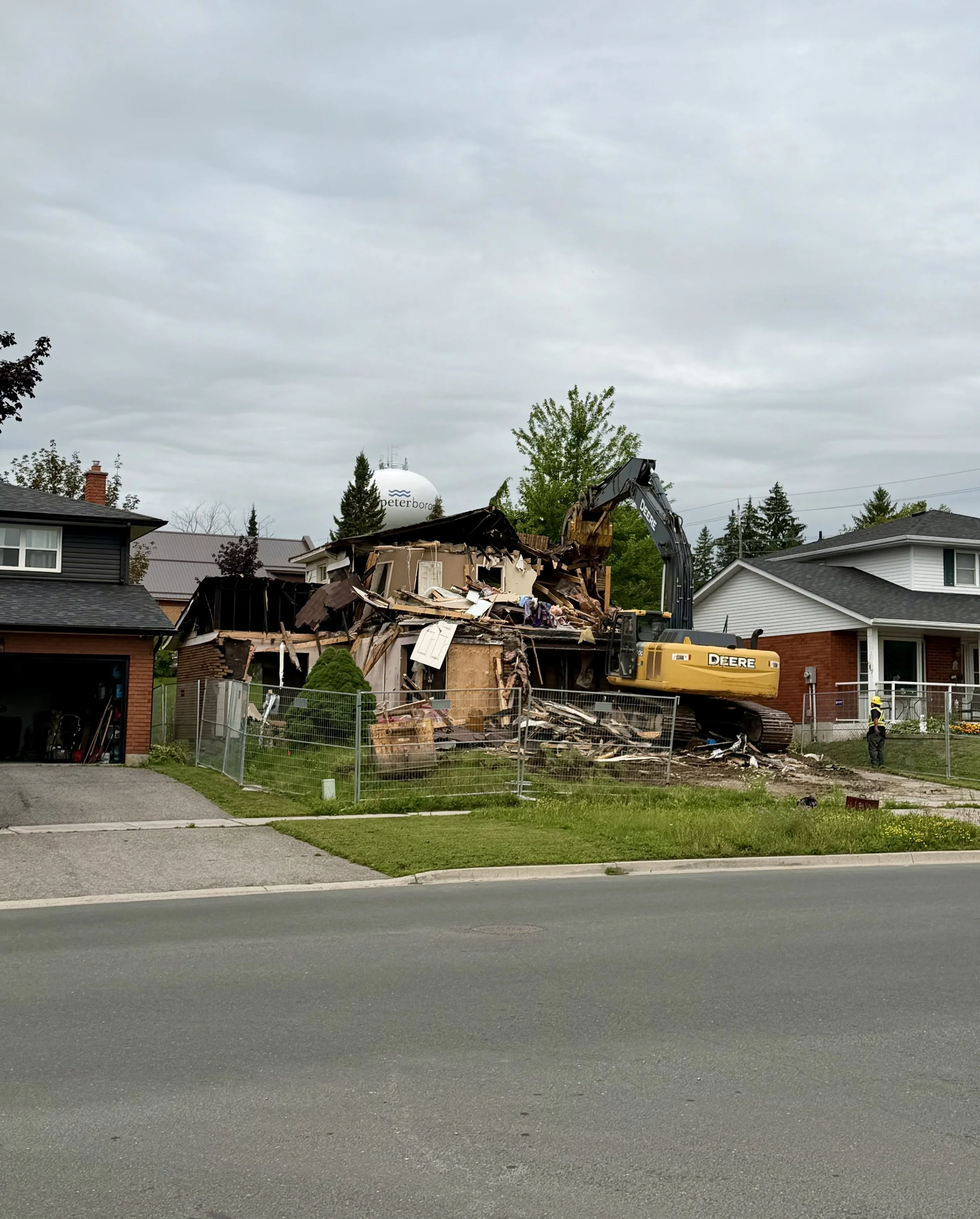 The first stages of demolition were underway Monday as an excavator began tearing down the Woodglade Boulevard property. (Photo by Scott Arnold)