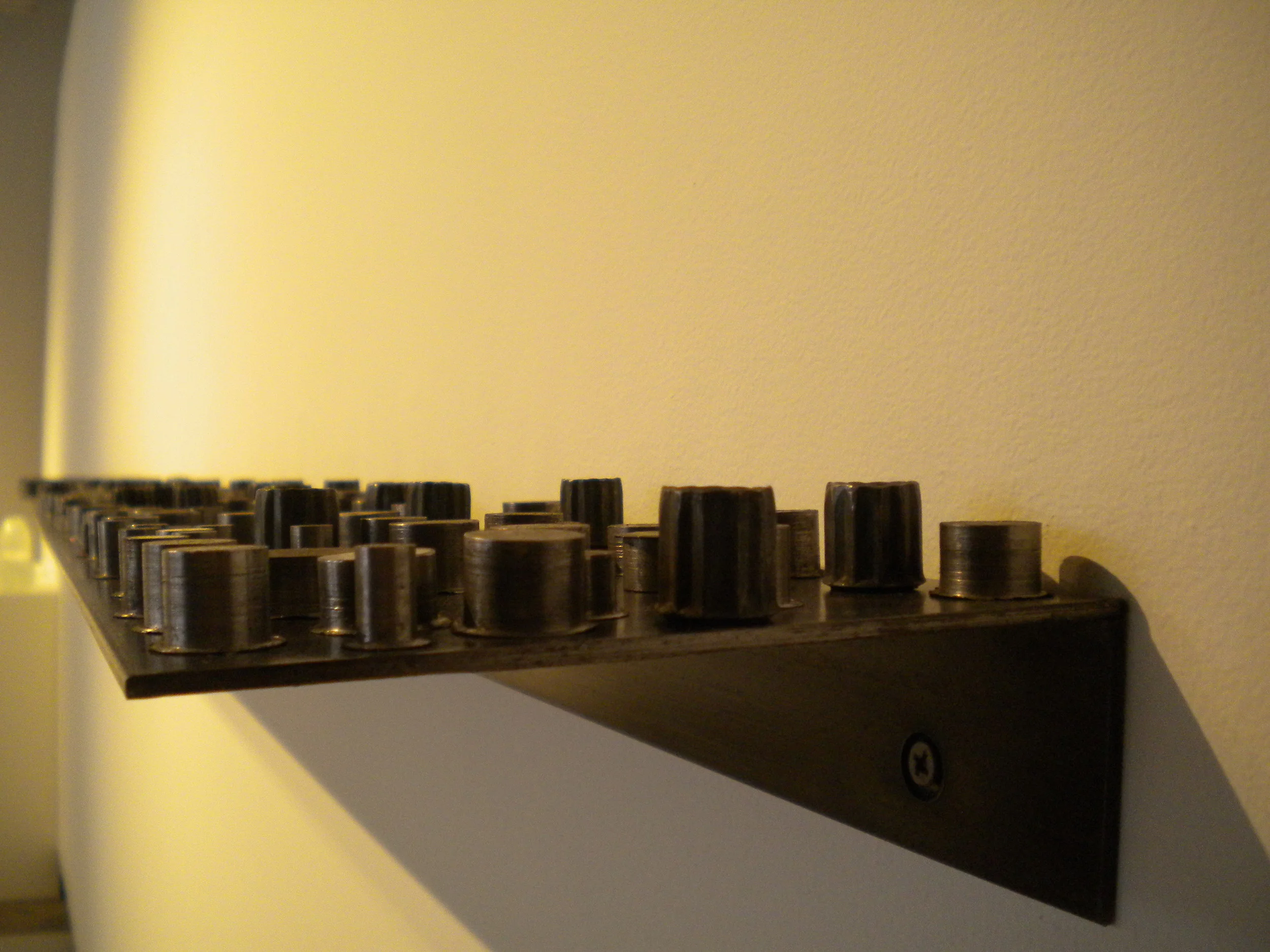   Slugs.  2 @ 48”x8”.   Steel shelves.  Collected and arranged steel blanks leftover from the drilling process.  