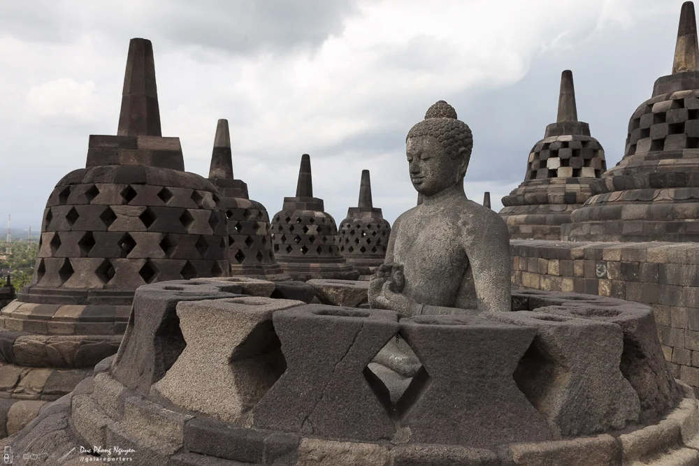 Buddha sculpture seated amid stupa-like structures at Borobudur temple in Indonesia