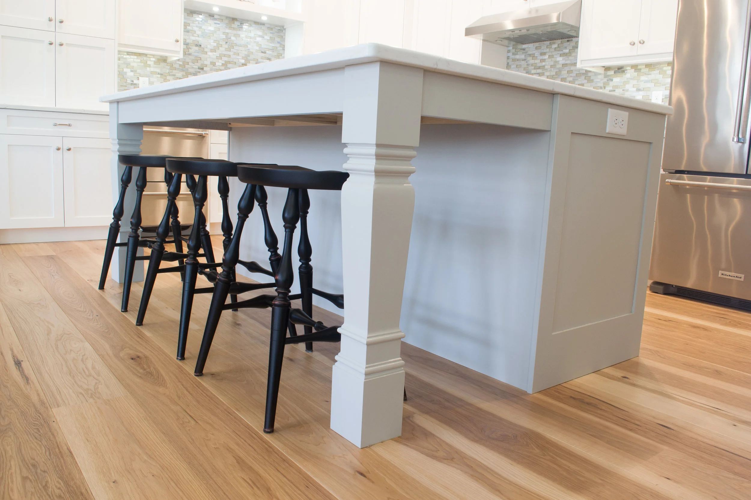 White painted kitchen with custom ornate grey island and shaker cabinets