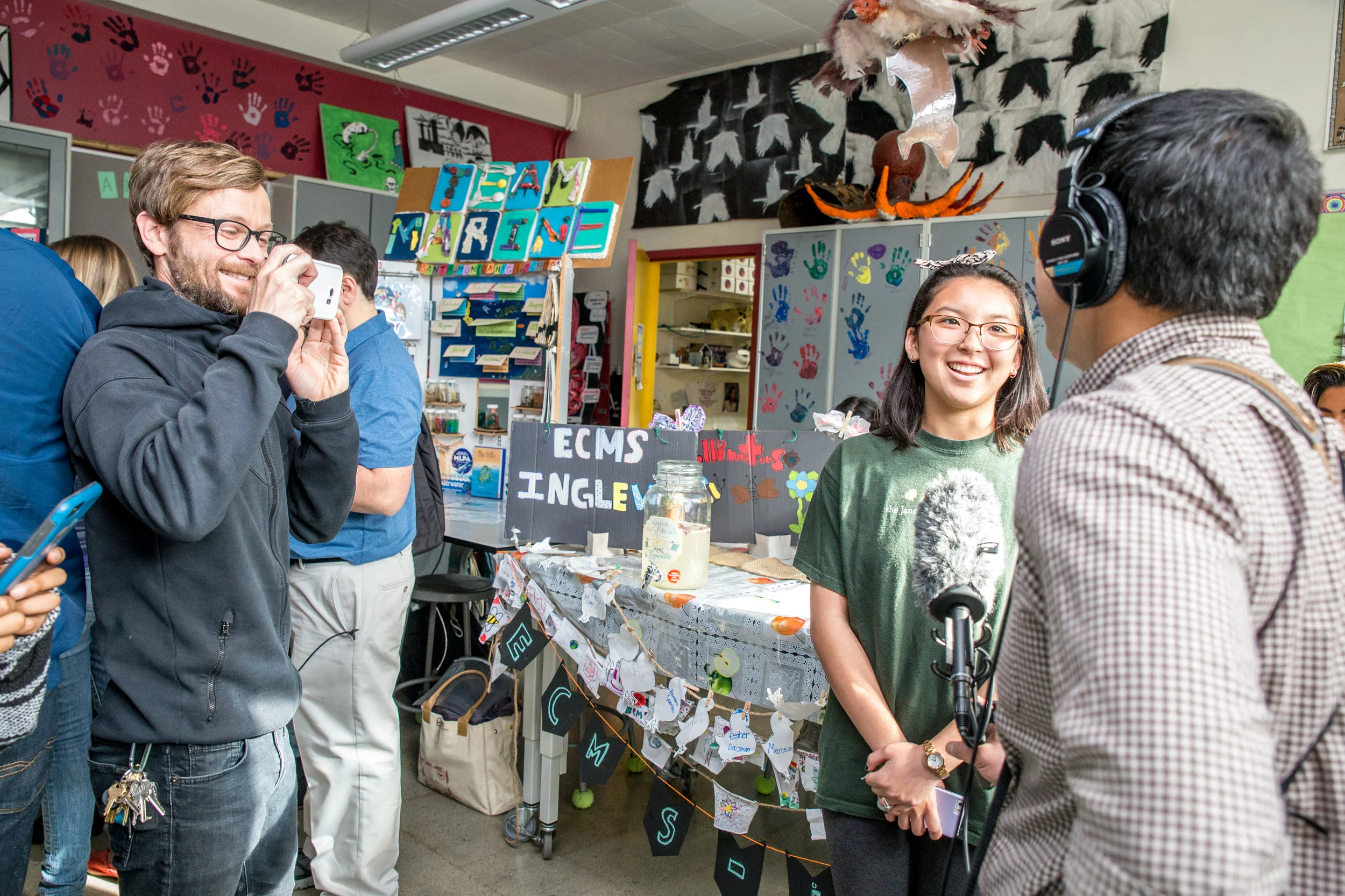 Katie Osaki (Jr) is interviewed by local radio while Mr. Kay captures the moment on video.