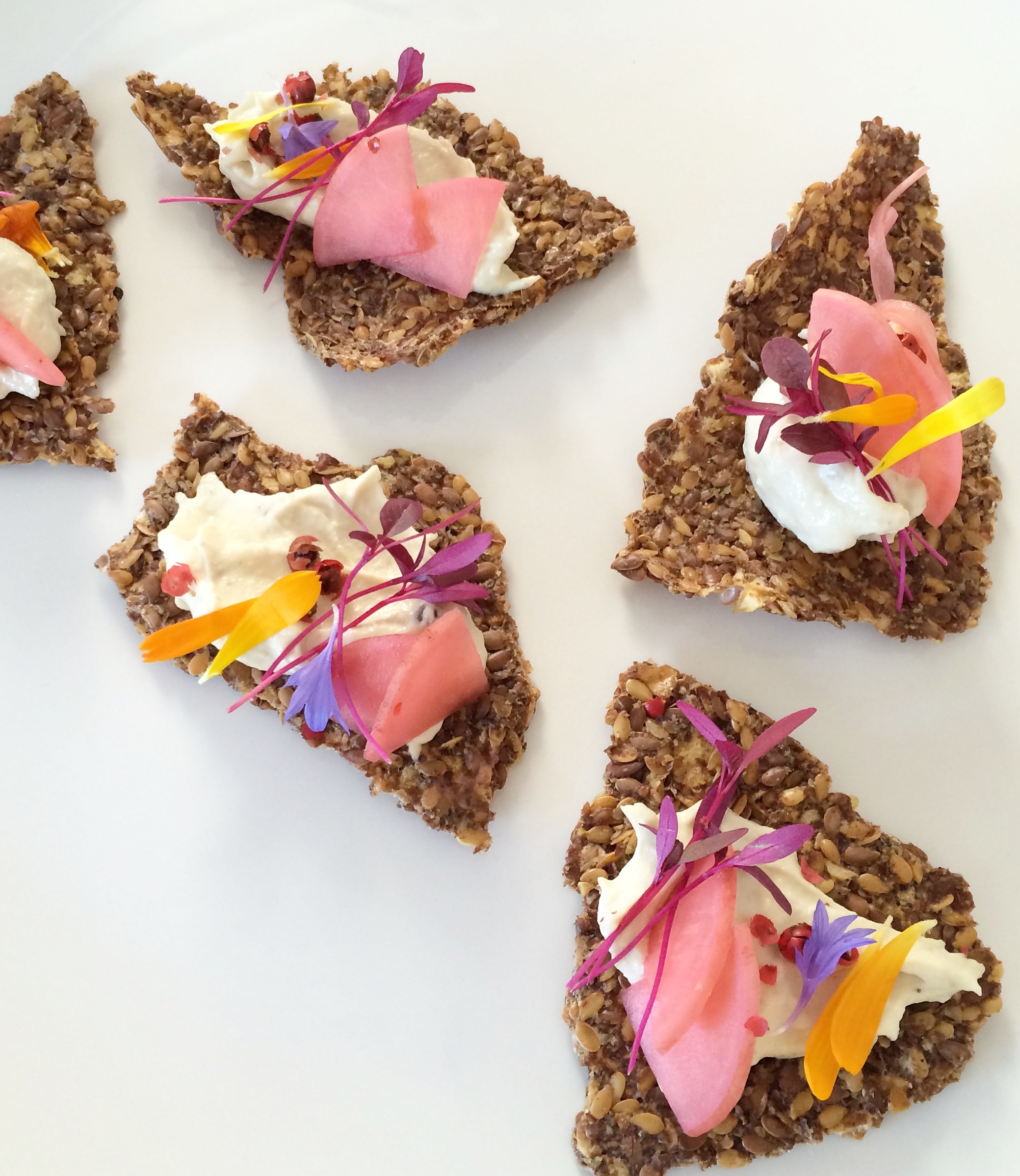 Red peppercorn fermented cashew cream cheese on flax crackers. Pickled radish. Amaranth microgreens. Flowers.