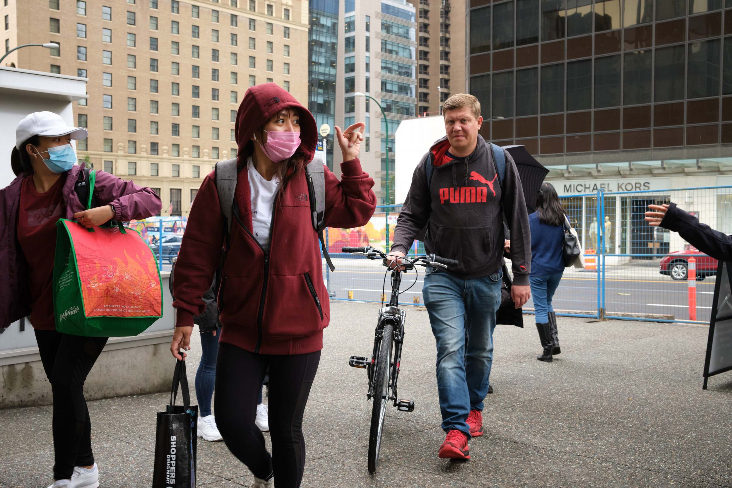 A woman waves to a friend and wearing a face mask in downtown Vancouver