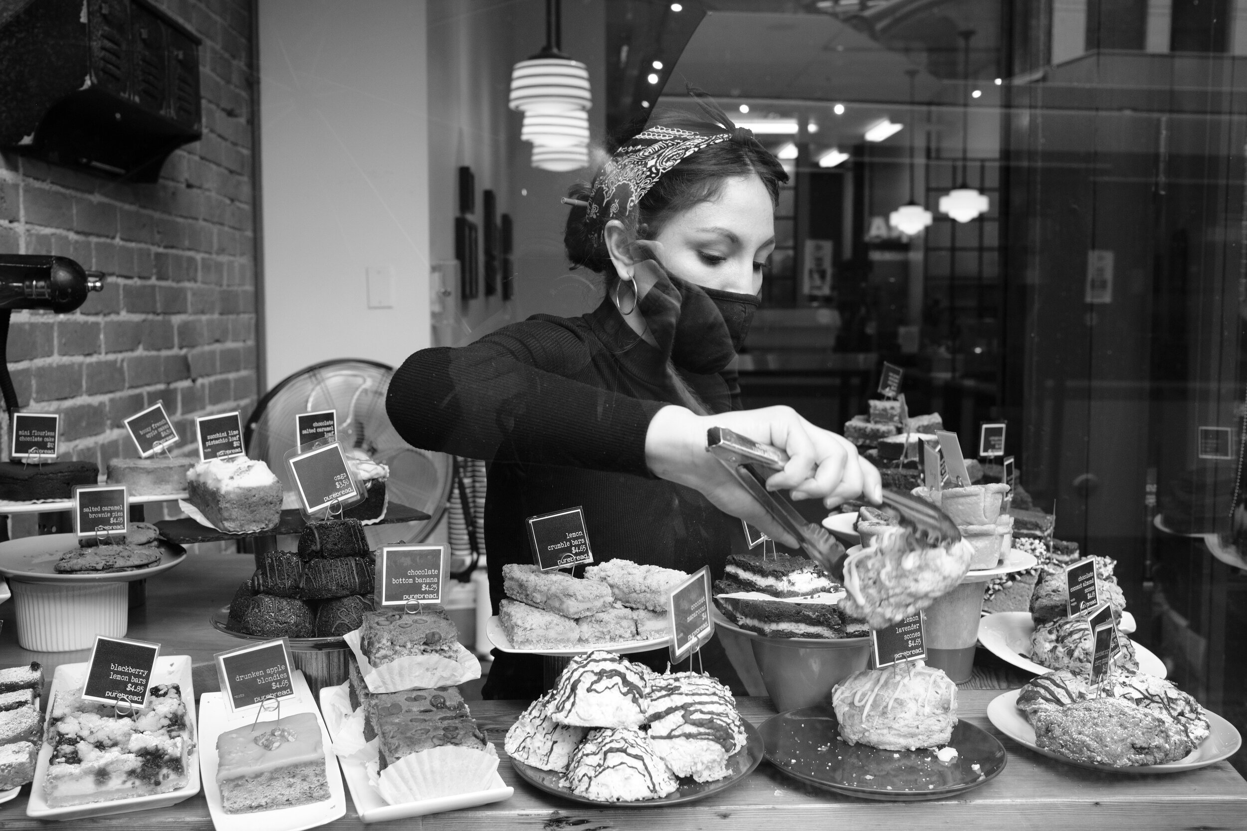 A woman in West Hastings bakery finds a bread for a customer in a window display