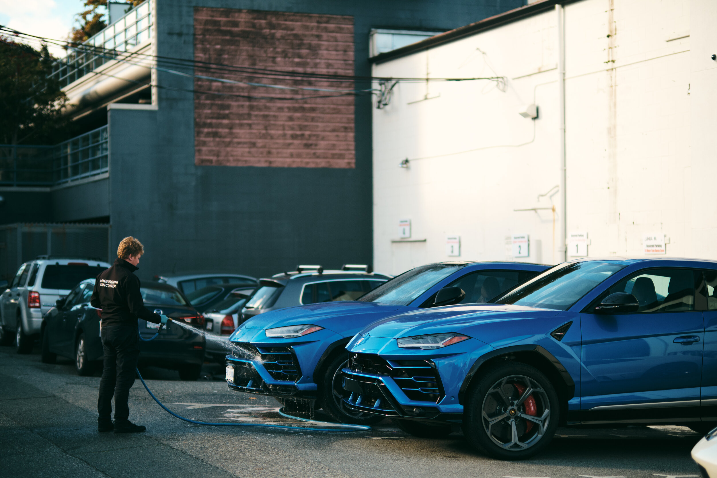 A young man washes two blue Lamborghini Urus SUVs in Vancouver. Sample image from a Fujifilm XF 50mm f/1 R WR