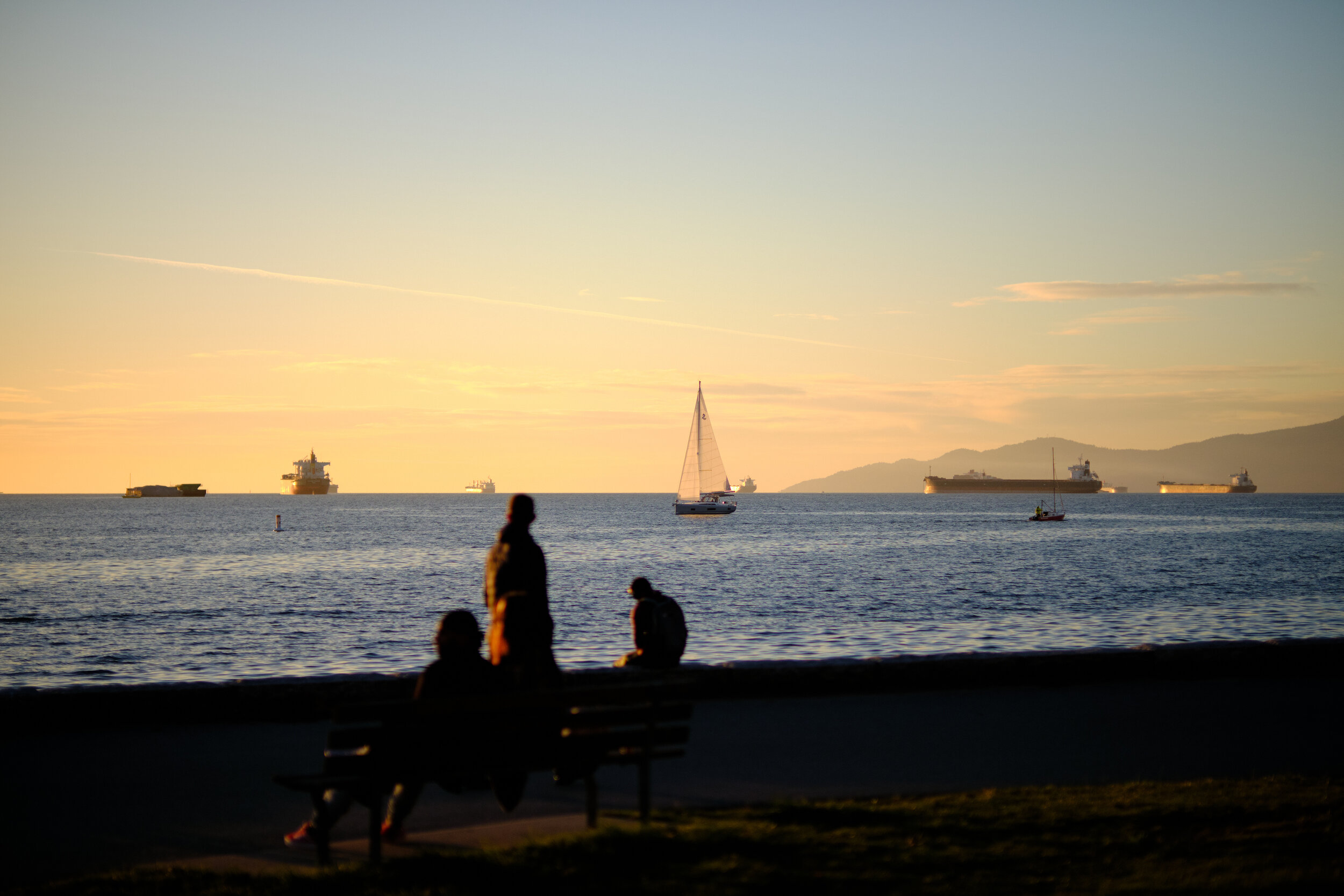 Friends hang out on English Bay Beach in Vancouver at sunset on a fall evening. Sample image from a Fujifilm XF 50mm f/1 R WR